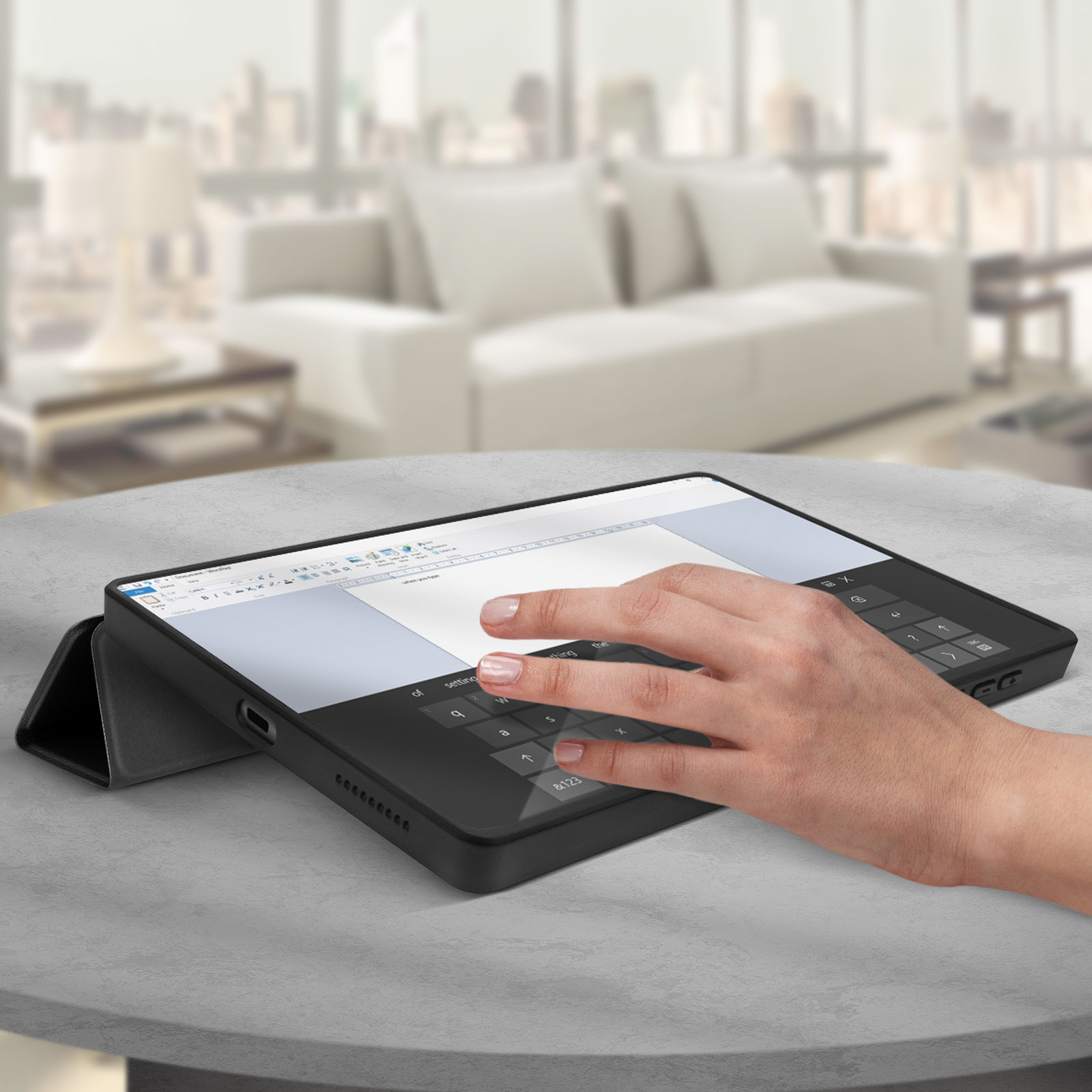 Tablet con custodia tastiera su un tavolo. Mano che digita. Città sfocata sullo sfondo.