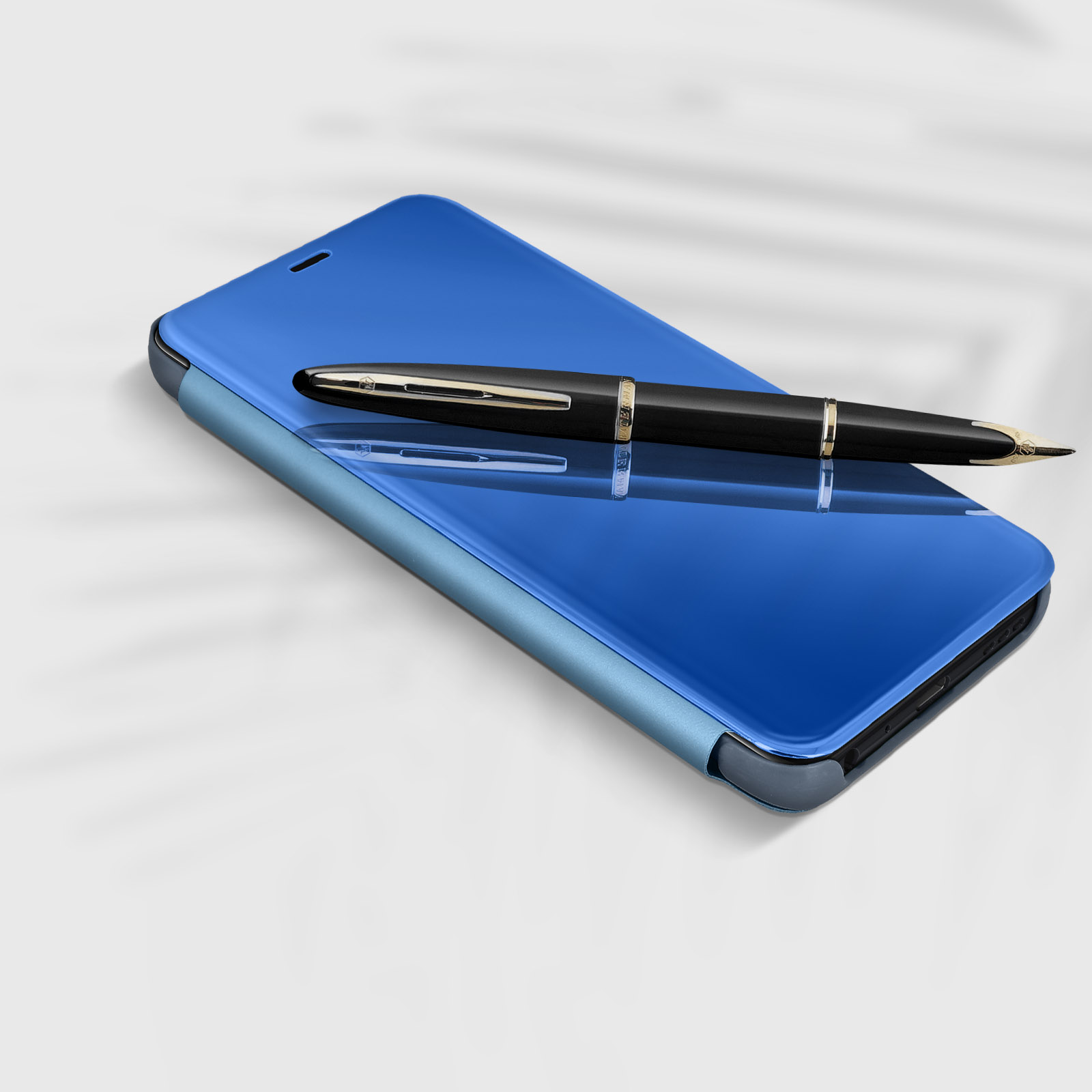 Coque de téléphone bleue avec un stylo posé dessus. L'étui est sur une surface blanche.