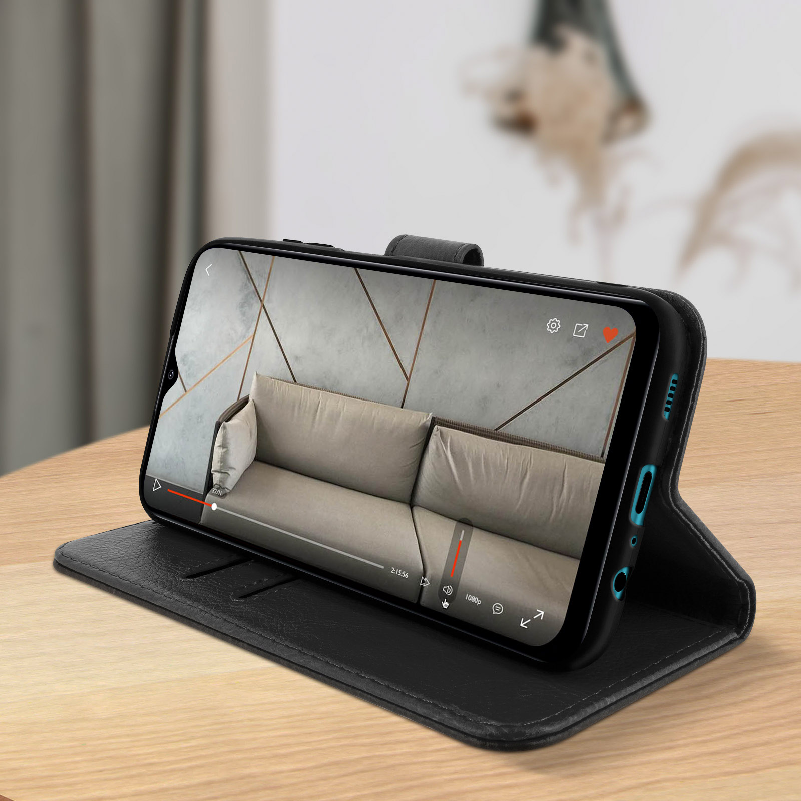 Un téléphone affiche une vidéo, posé sur une table en bois. Un étui noir maintient le téléphone.