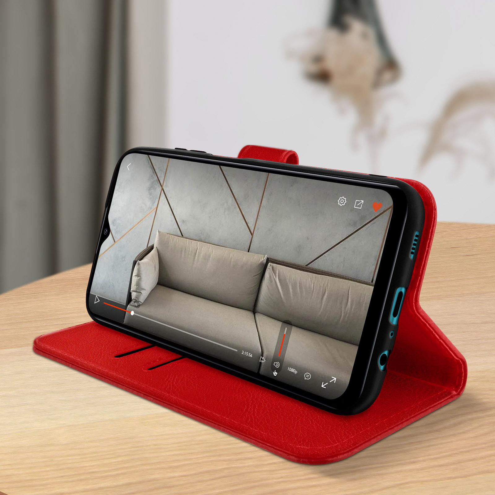 Un étui de téléphone rouge ouvert pour montrer un téléphone affichant une vidéo sur une table en bois.