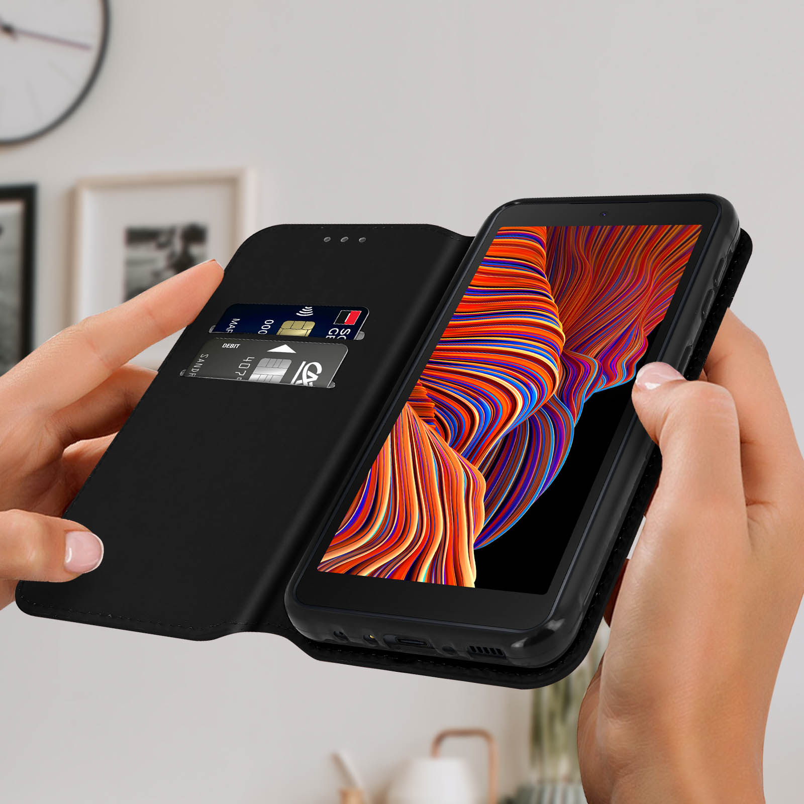 Mains tenant un téléphone ouvert, montrant des cartes de crédit dans une fente et un écran coloré.