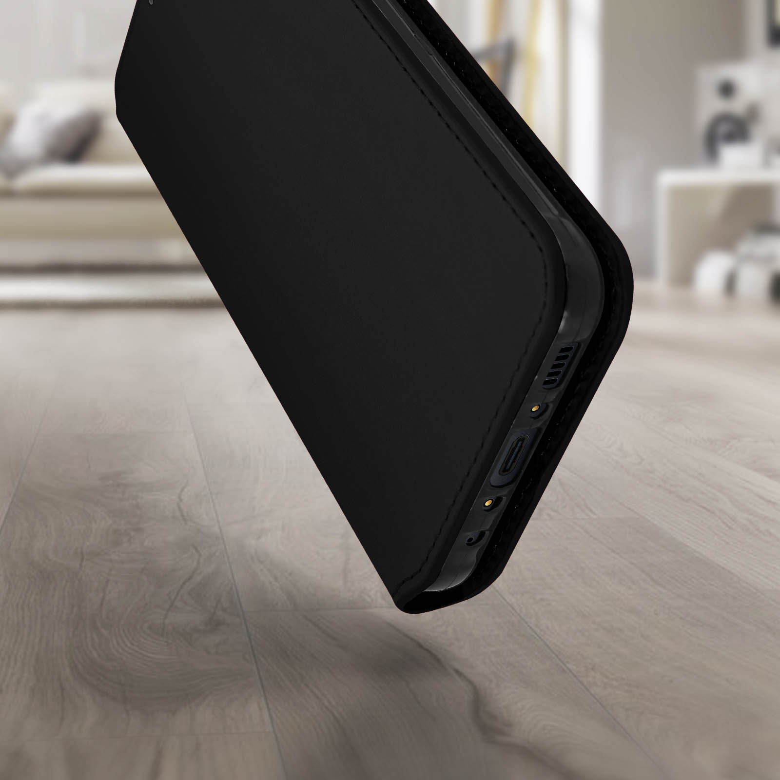 Étui de téléphone noir sur un plancher en bois. L'étui est ouvert, révélant le bord du téléphone.