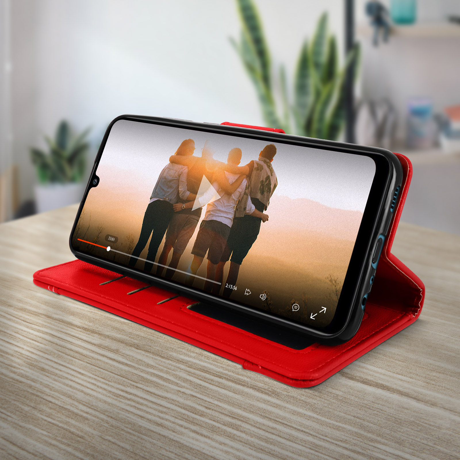 Telefoon in rode hoes met een video. De telefoon ligt op een houten tafel.