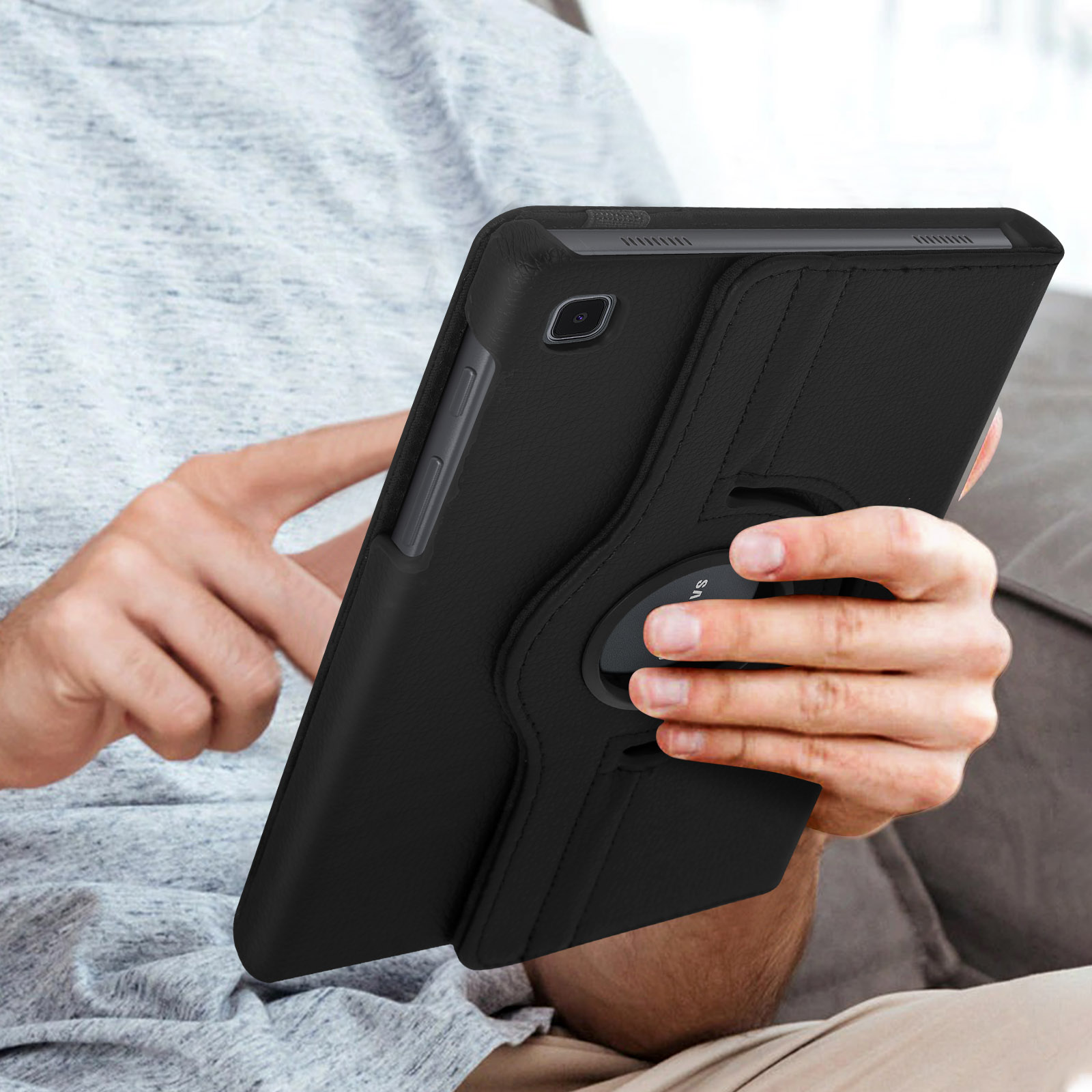 Una persona che tiene un tablet nero in una custodia nera. La persona è seduta su un divano.