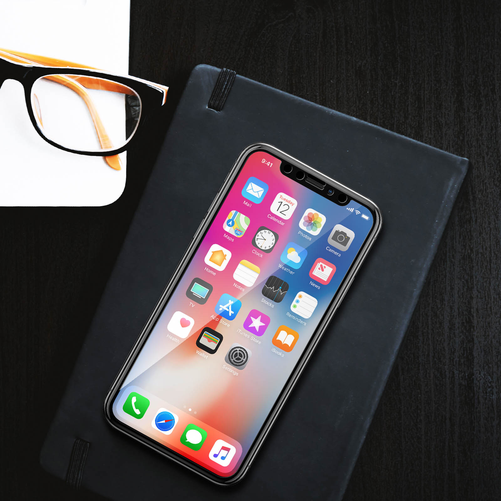 Un telefono su un taccuino con protezione schermo. Lo schermo mostra icone di app e un orologio.
