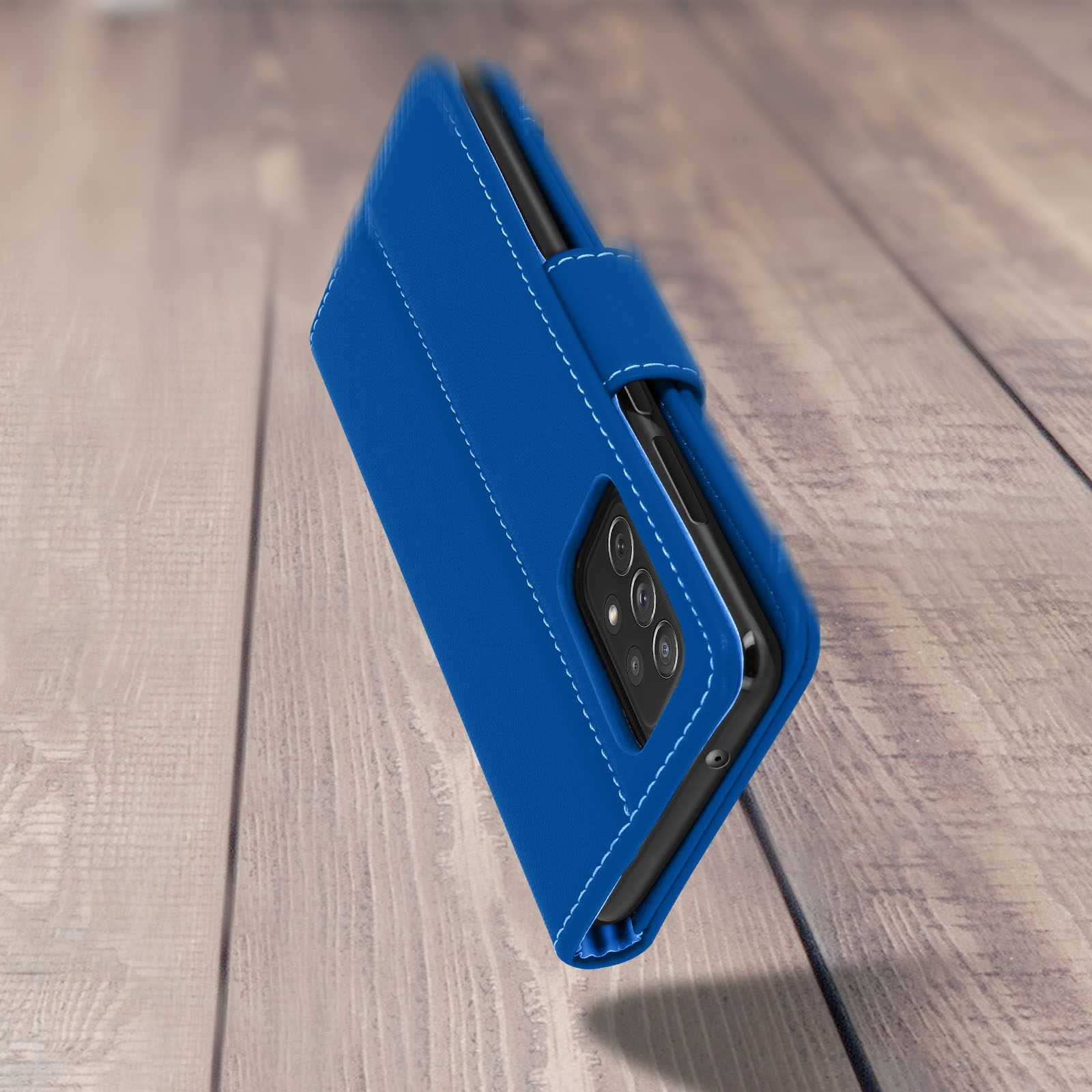 Custodia blu per telefono con cucitura bianca. Il telefono è su un tavolo di legno. Vista laterale.