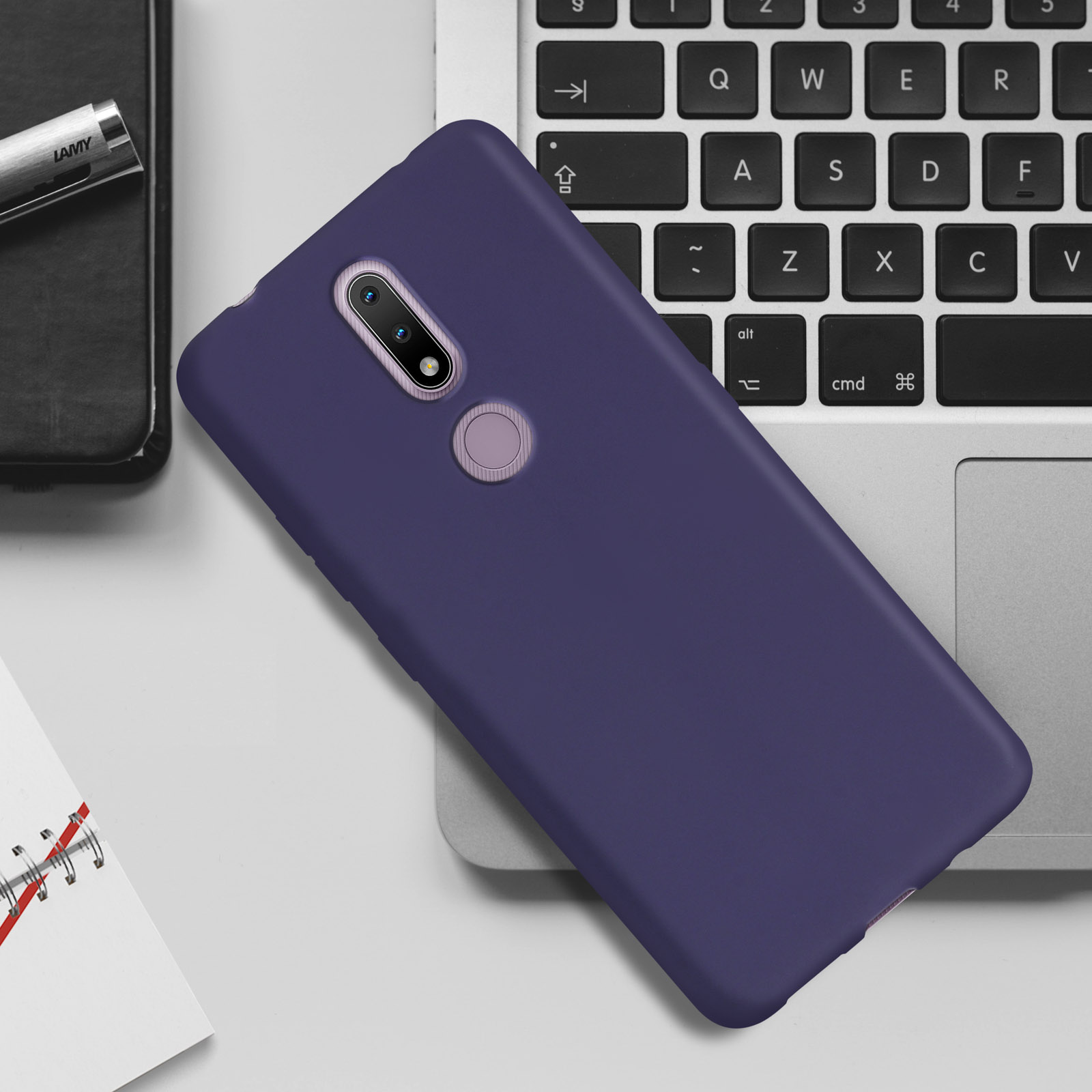 Custodia viola su un laptop, con penna e blocco note sullo sfondo.