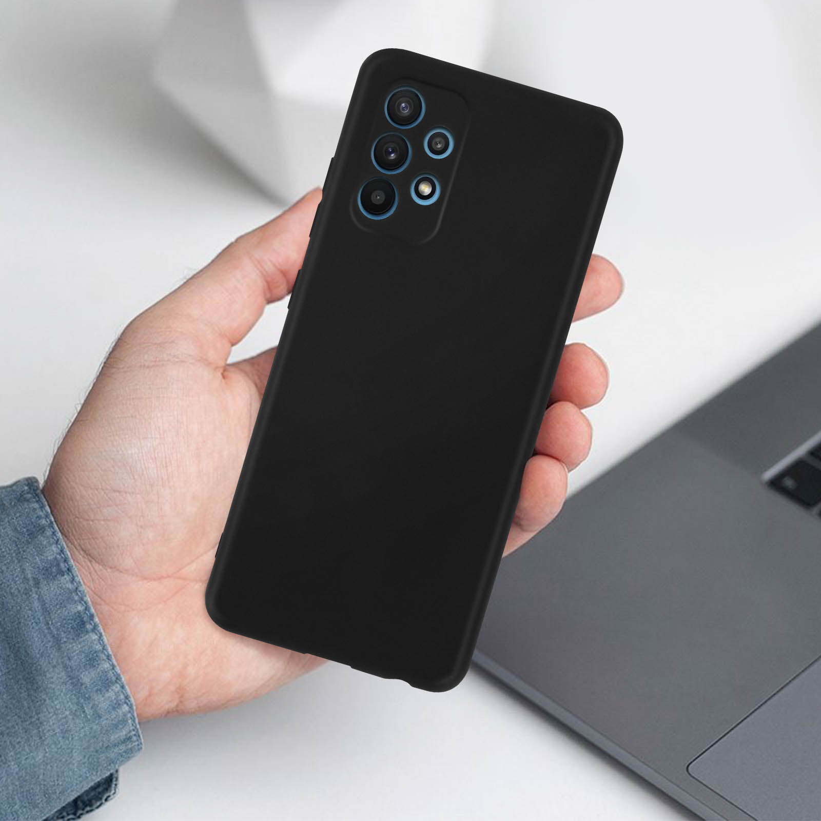 Hand hält schwarzes Telefon mit schwarzer Hülle, grauer Hintergrund.