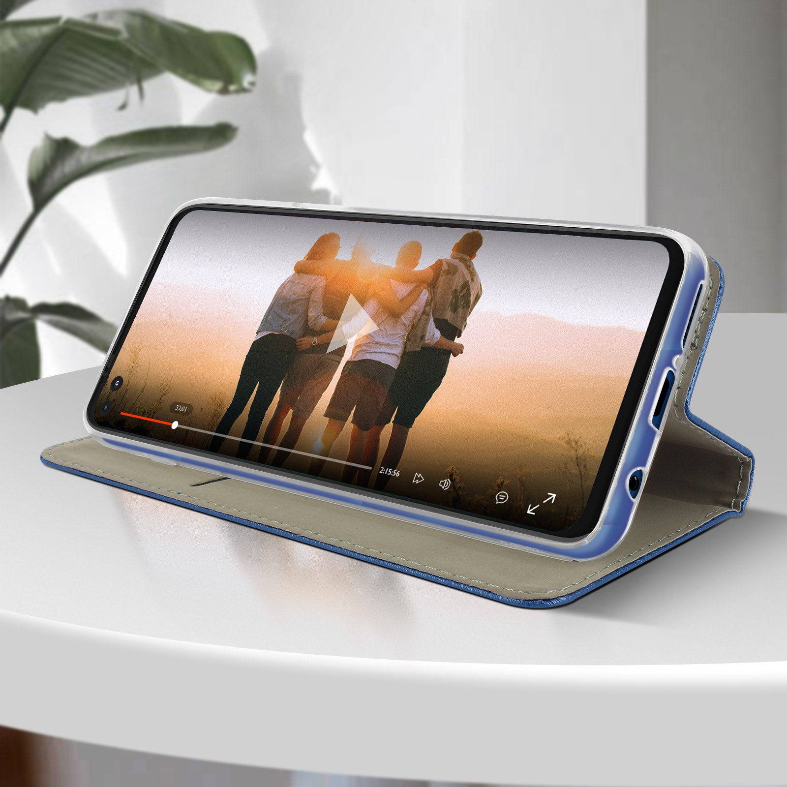 Custodia del telefono, aperta, che mostra video. Persone al tramonto. Su tavolo bianco, copertura blu.