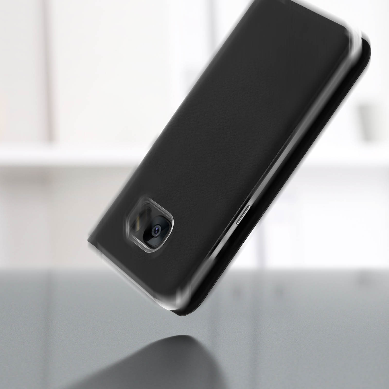 Custodia nera per telefono che cade. L'obiettivo della fotocamera è visibile. Sfondo grigio.