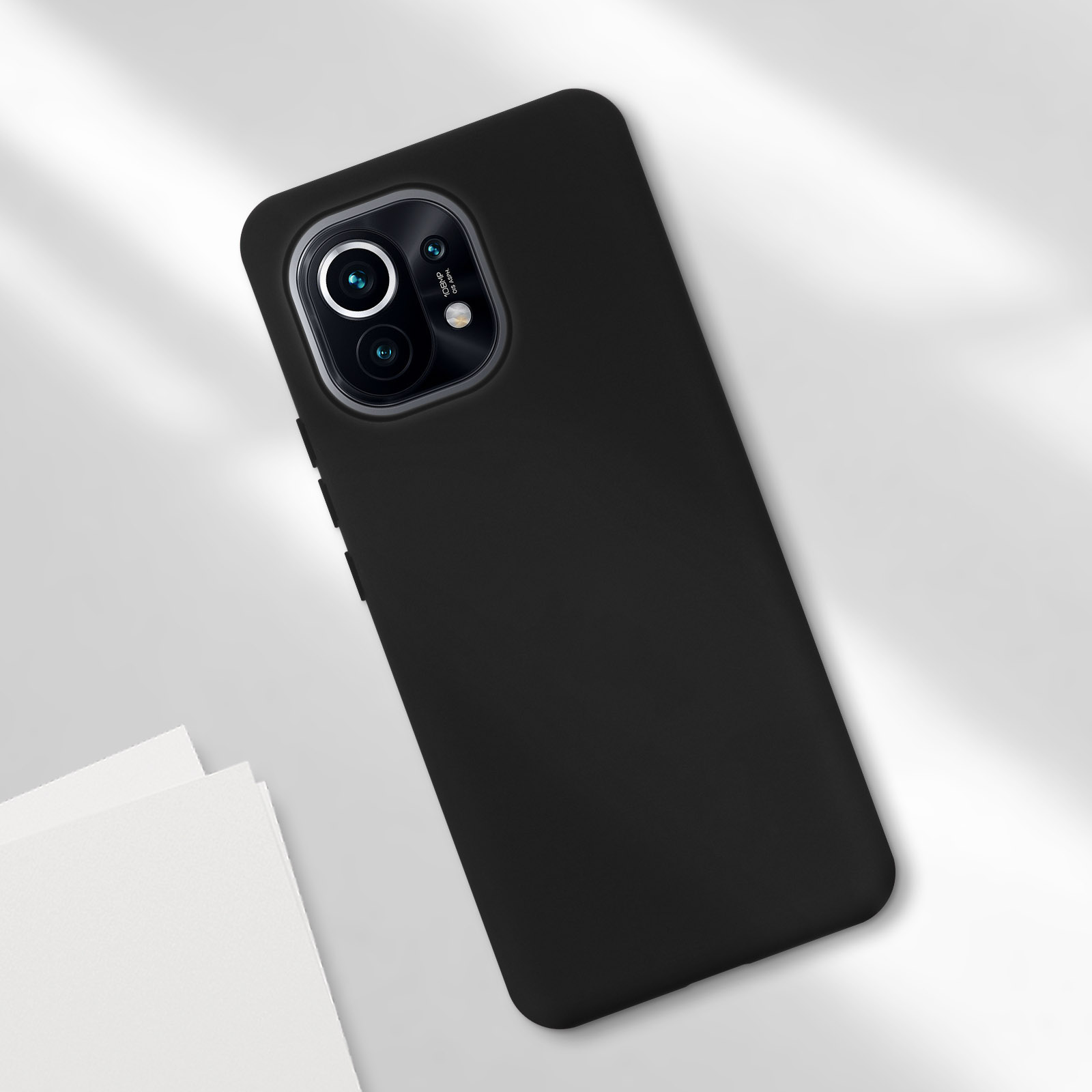 Una custodia per telefono nera con una fotocamera, visualizzata su una superficie bianca. Il telefono è angolato.