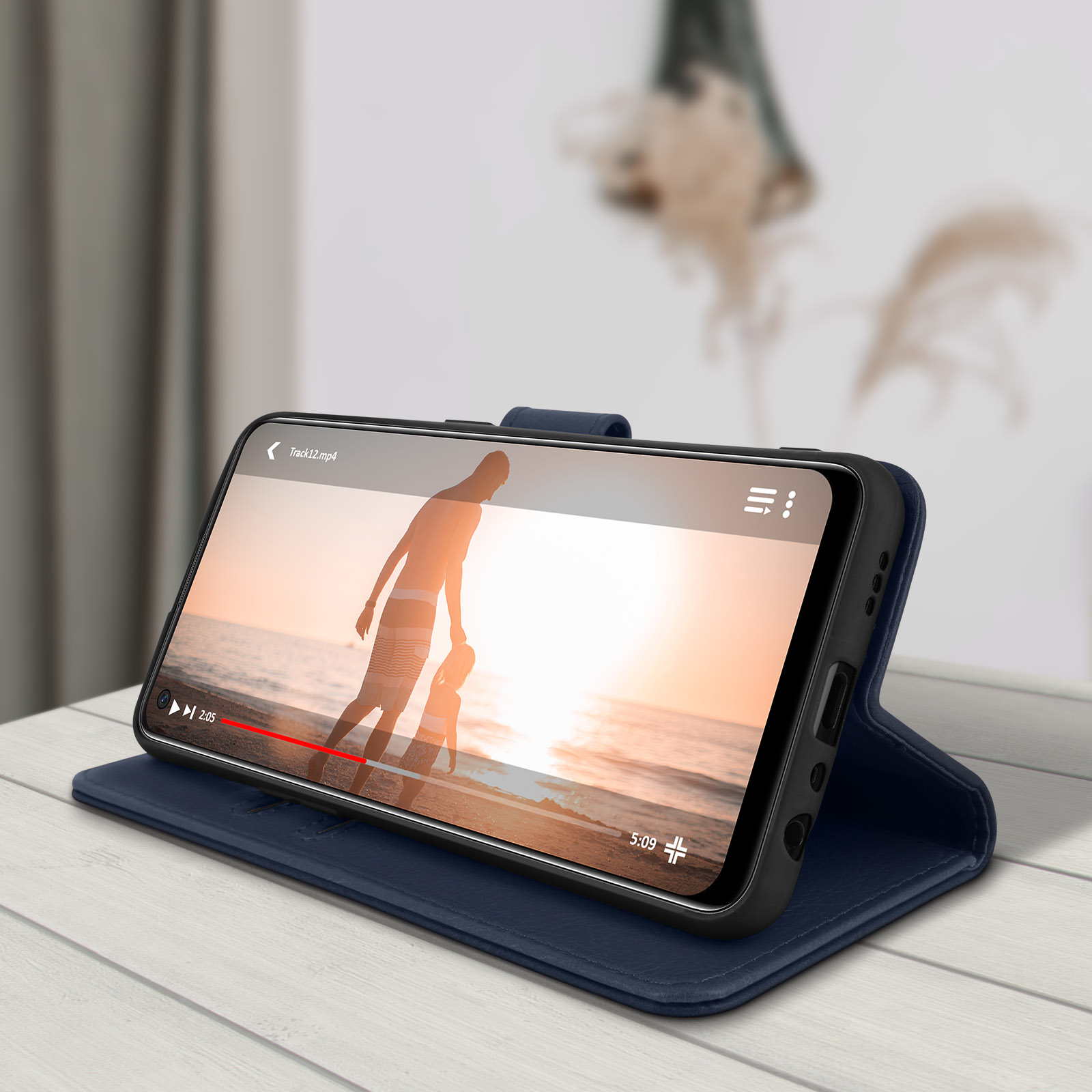 Telefono con custodia aperta. Video in riproduzione sullo schermo. Tavolo in legno.