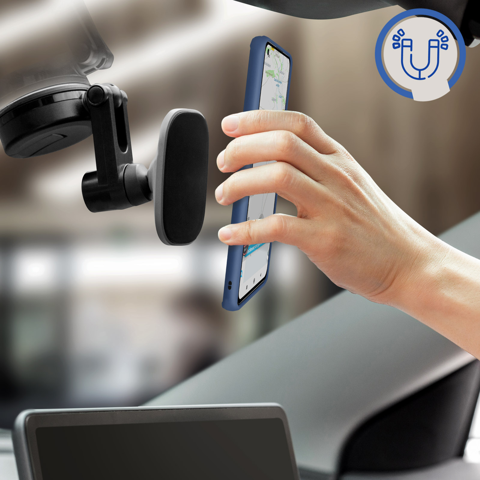 Une main tenant un téléphone avec un étui bleu, près d'un pare-brise de voiture avec un support.
