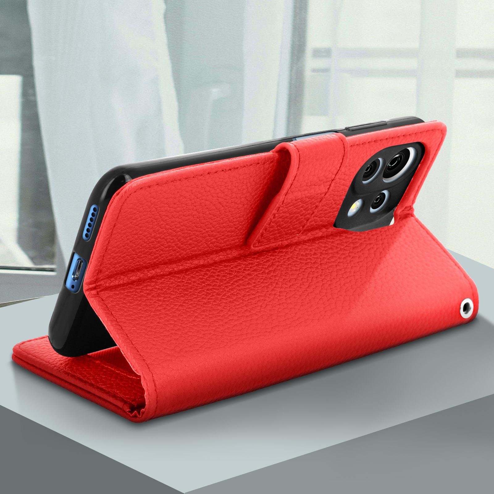 Custodia del telefono rossa aperta, con un telefono all'interno. La custodia è simile alla pelle e il telefono è su un tavolo.