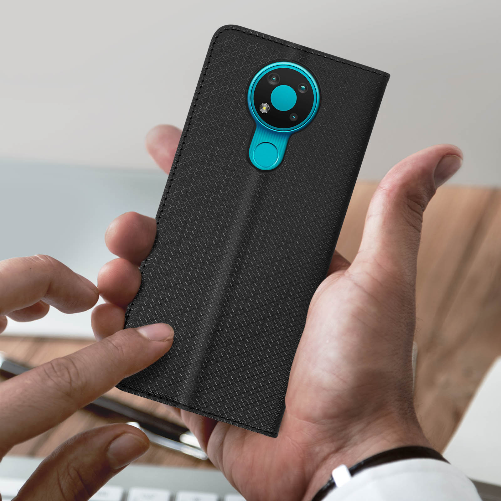 Custodia nera con una grande fotocamera. Mano che tiene la custodia. Lo sfondo è sfocato.