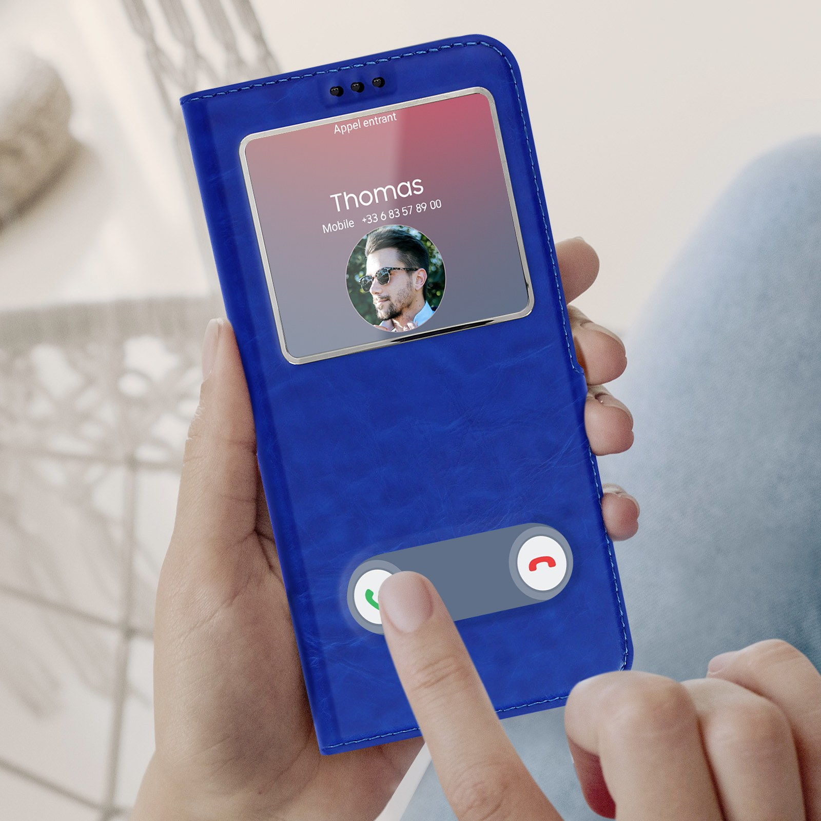 Téléphone affichant un écran d'appel. Le téléphone est dans un étui portefeuille bleu, tenu par des mains.