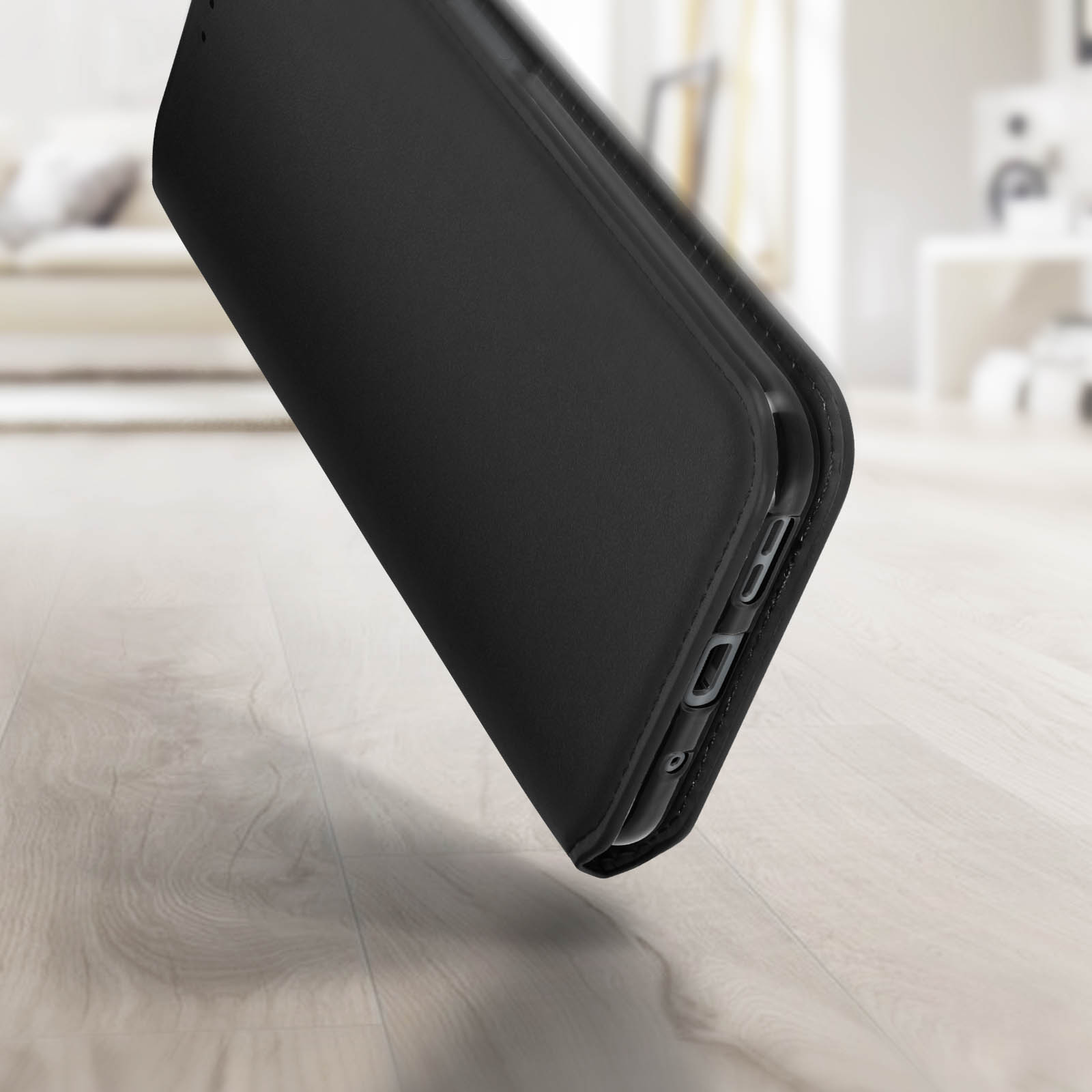 Una custodia per telefono nera con un telefono nero all'interno, inclinata su una superficie di legno.