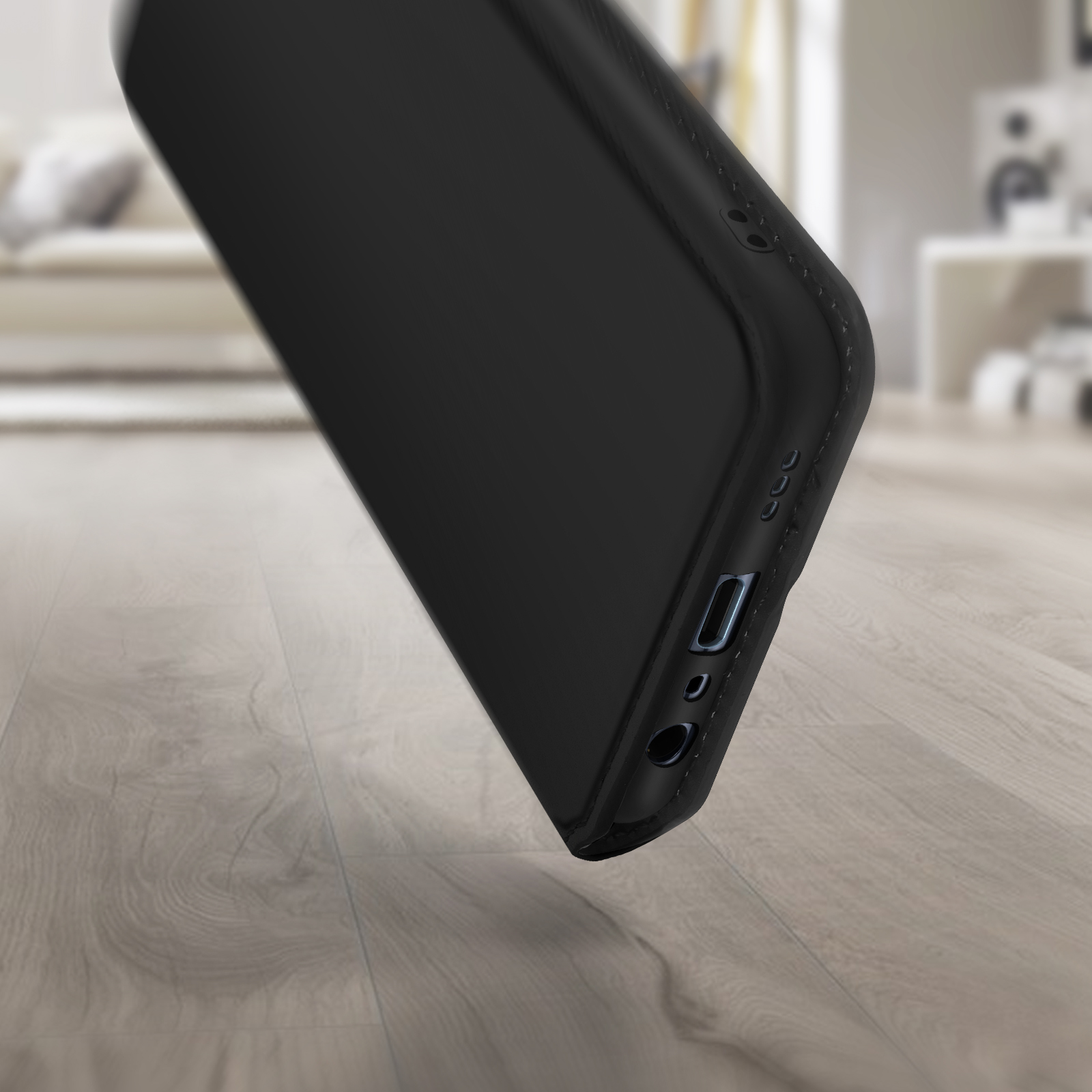 Gros plan d'une coque de téléphone noire sur un plancher en bois, en angle.
