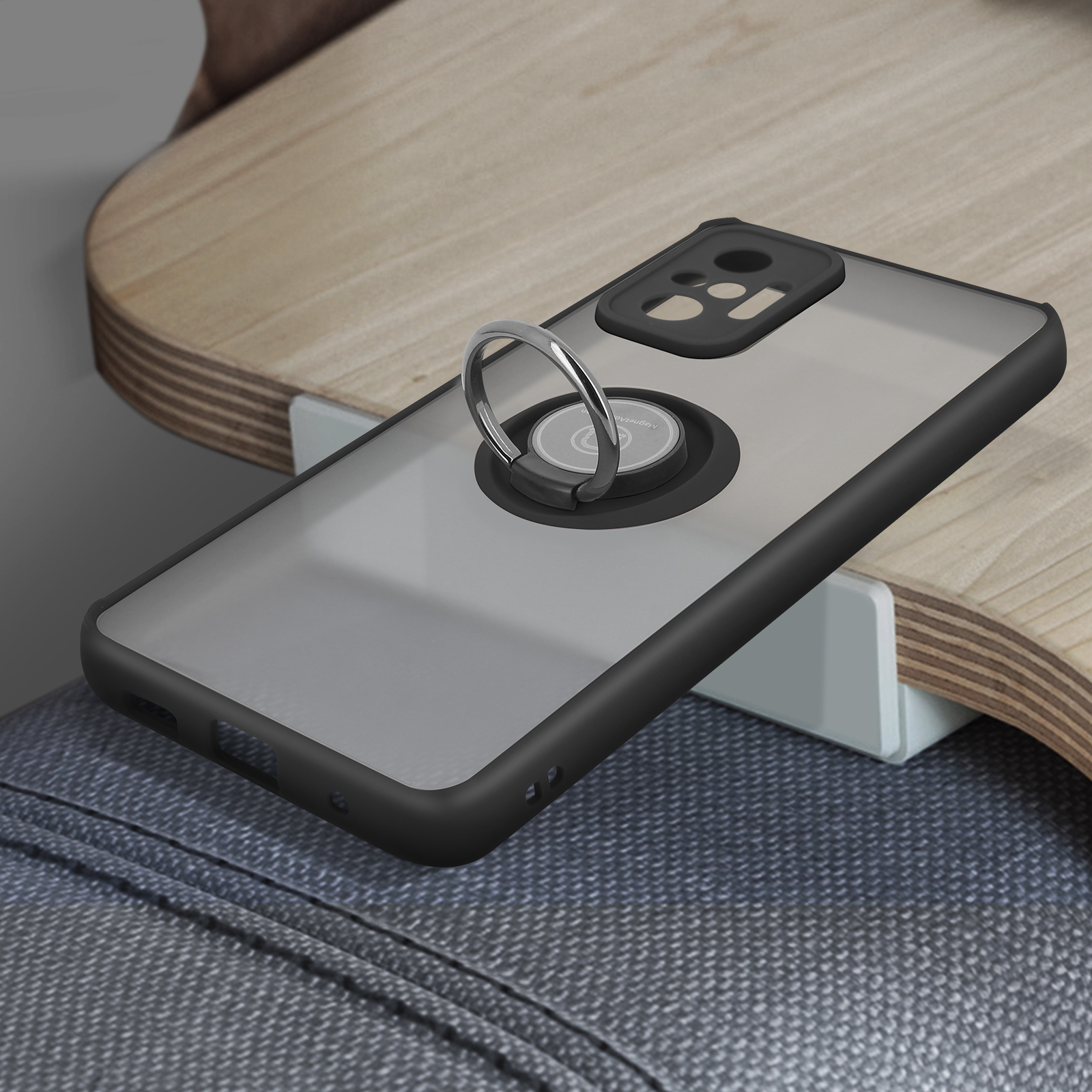 Telefoonhoesje met ringstandaard op een houten oppervlak. De hoes is zwart en transparant.