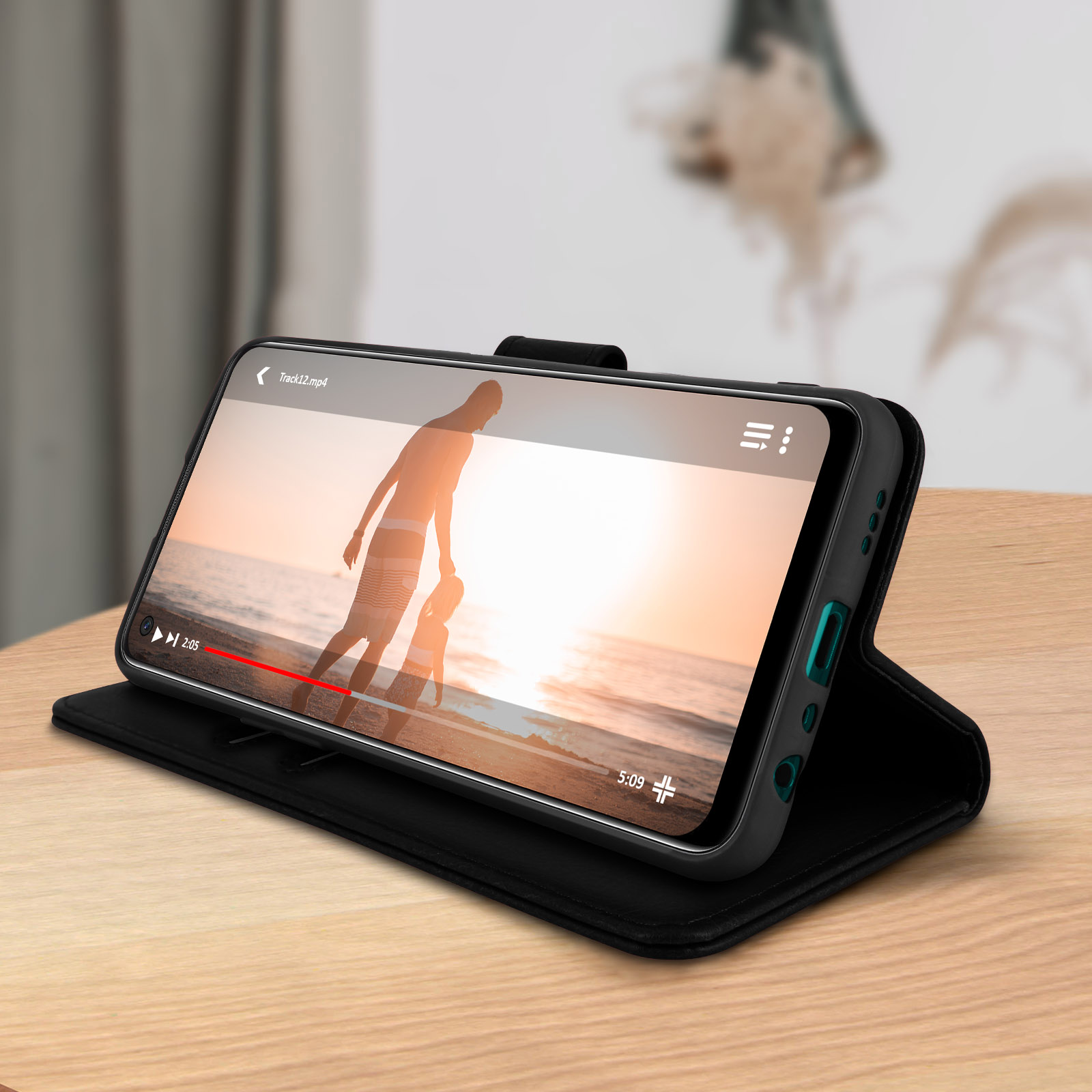 Un téléphone dans un étui noir est sur une table. Une vidéo est en cours de lecture sur l'écran.