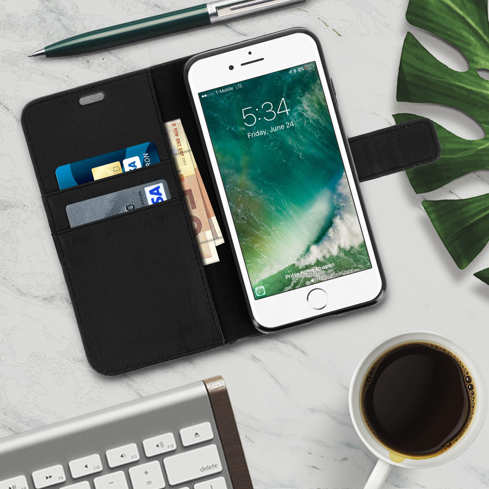 Telefono in una custodia nera con carte e denaro. Una tastiera e una tazza di caffè nella scena.