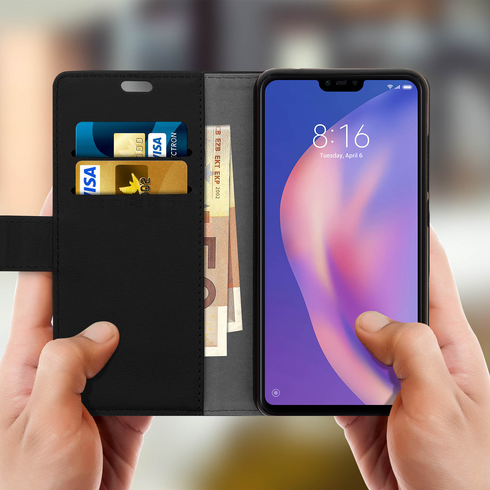 Mani che tengono una custodia nera con telefono. Carte e denaro visibili.
