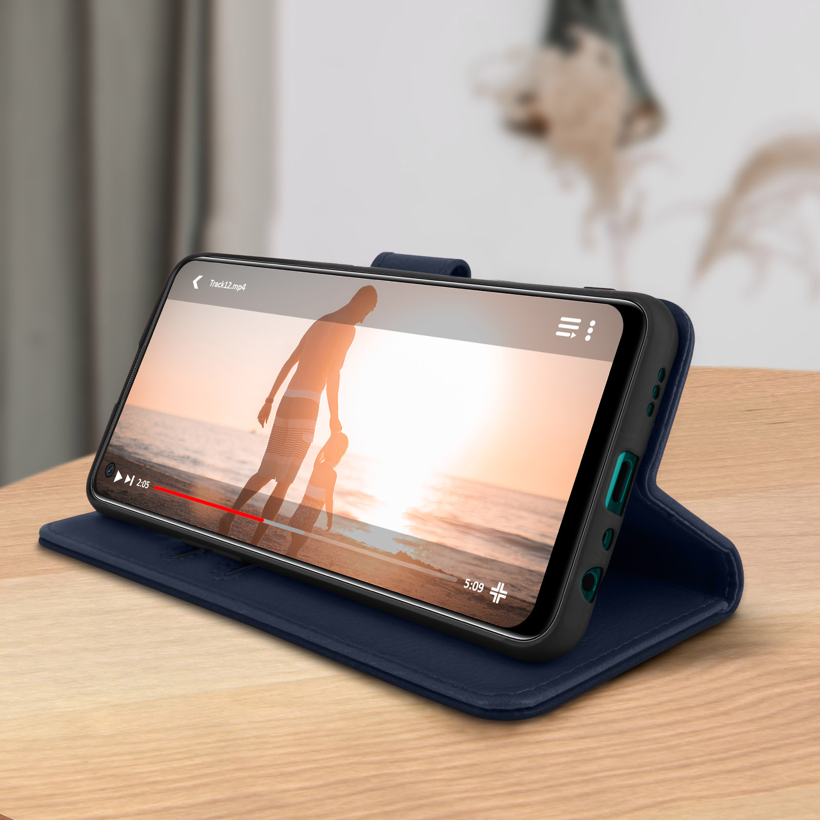 Téléphone affichant une vidéo. Étui bleu, ouvert. Surface en bois.