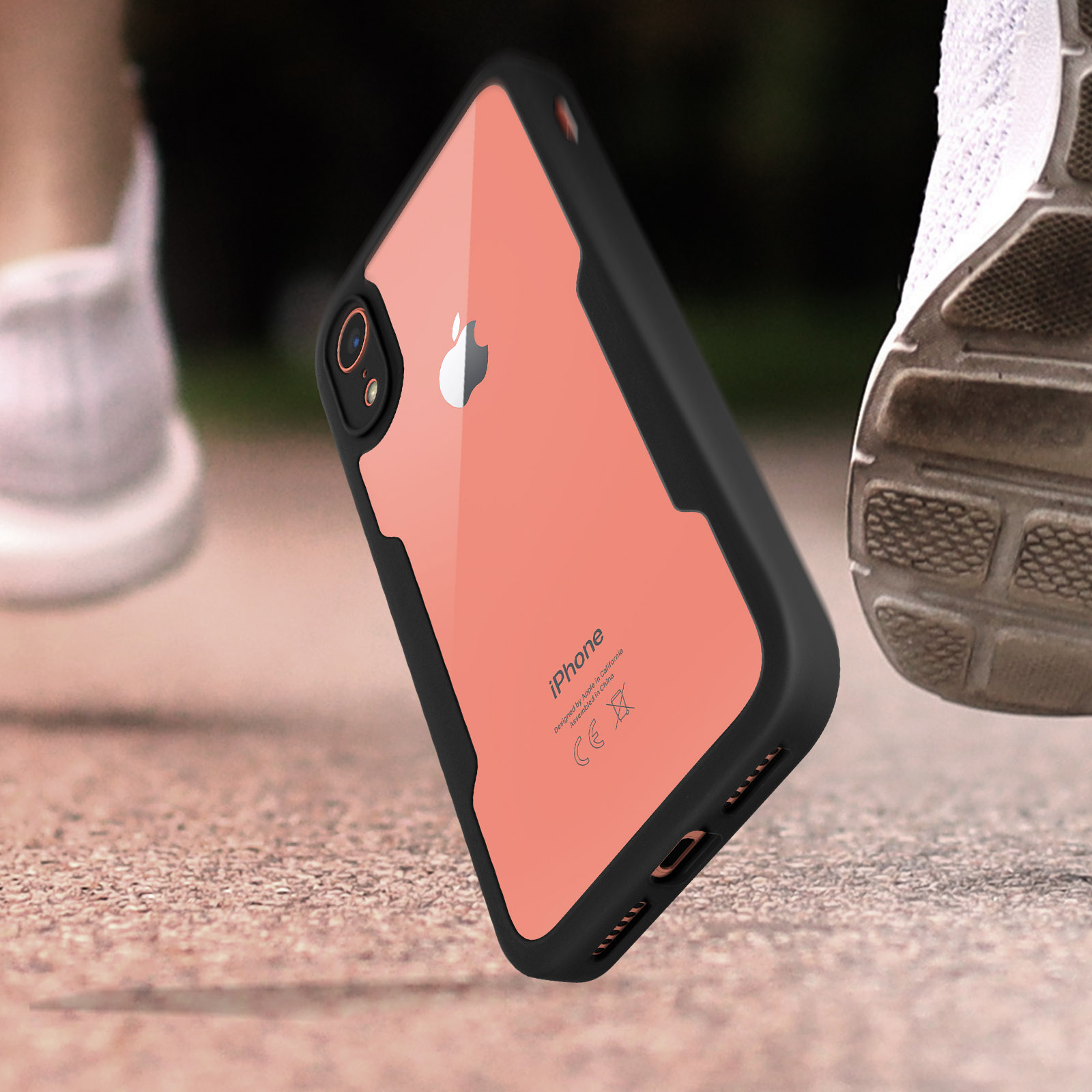 Un telefono in una custodia nera è su una strada. Una persona fa jogging sullo sfondo, con scarpe bianche.