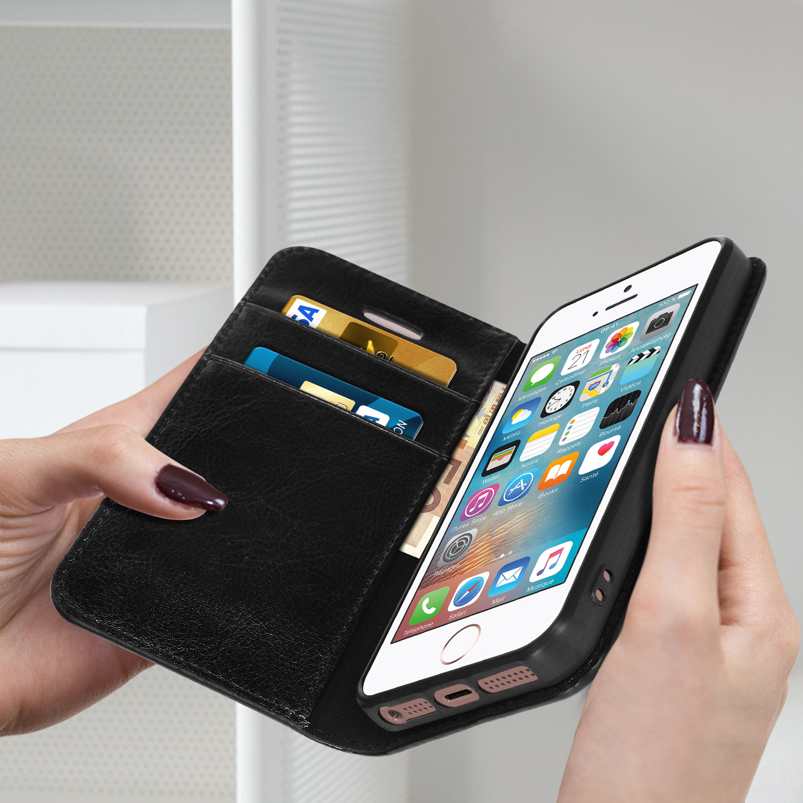 Una custodia per telefono nera con funzione portafoglio. Contiene telefono, carte e contanti. Una donna la tiene.