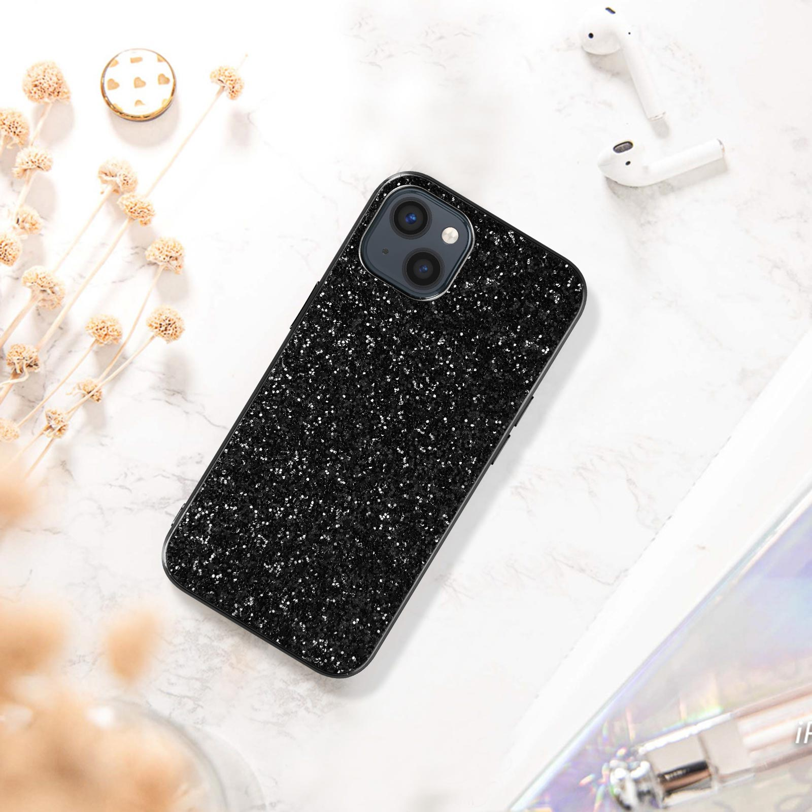Un telefono nero con glitter su una superficie di marmo bianco, con due auricolari wireless bianchi.