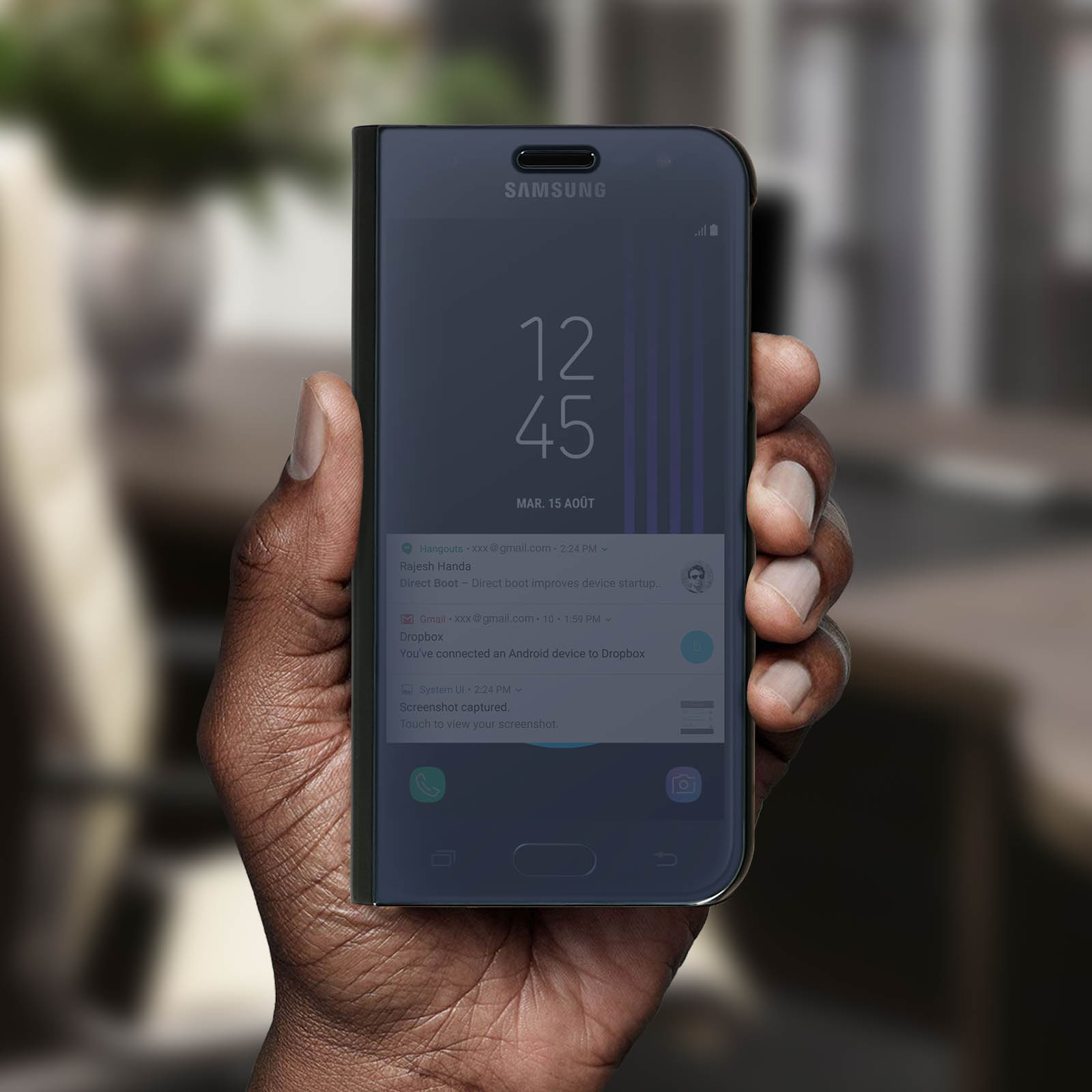 Mano che tiene un telefono. Telefono in custodia scura che mostra l'ora.
