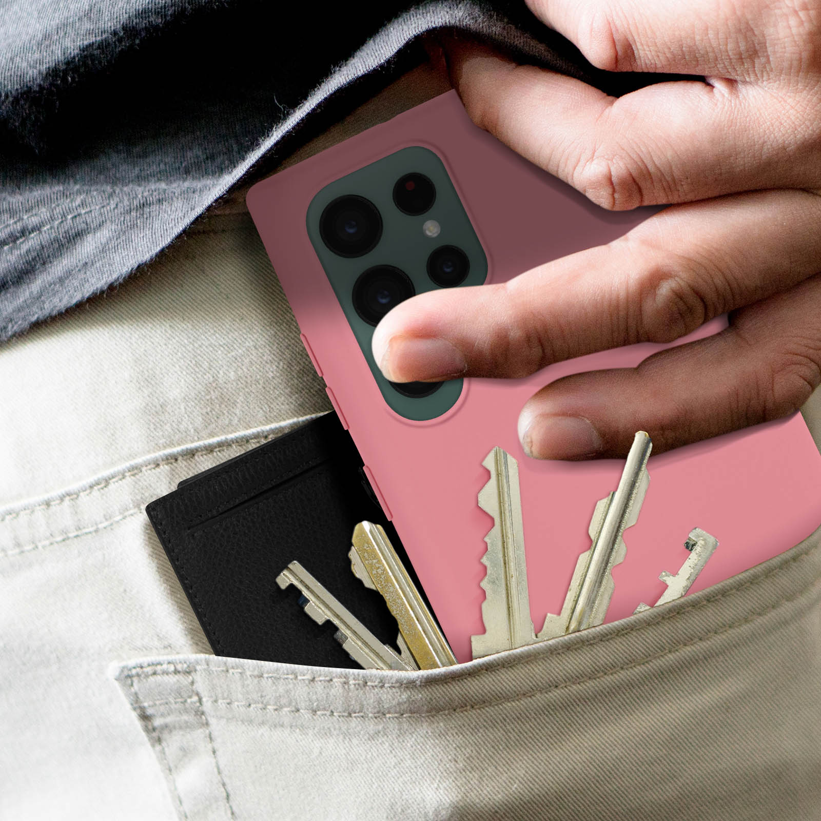 Hand einer Person mit Telefon und Schlüsseln in der Tasche. Rosa Handyhülle. Schwarze Brieftasche.
