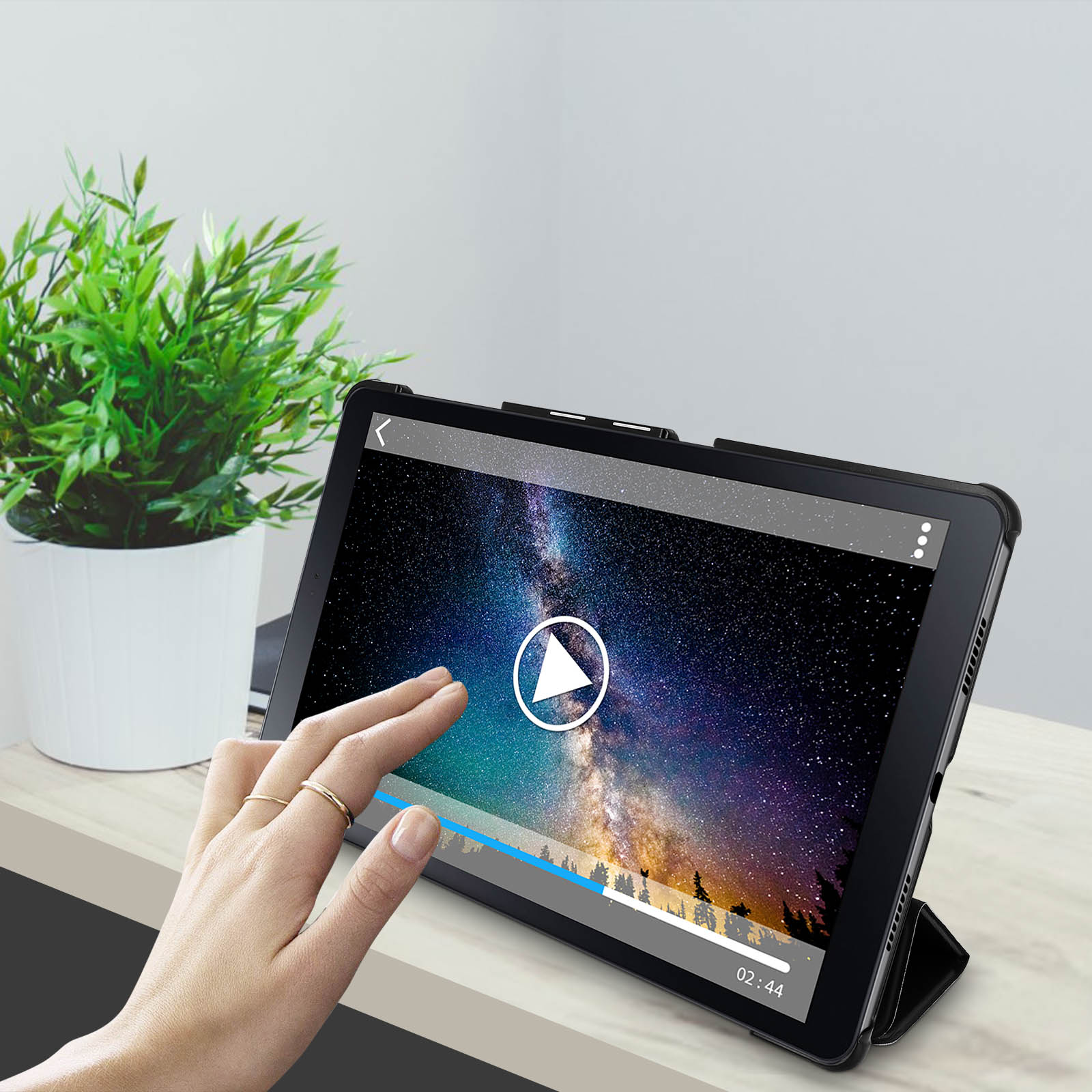 Tablet che riproduce video. Dito che tocca lo schermo. Pianta verde, sfondo bianco.