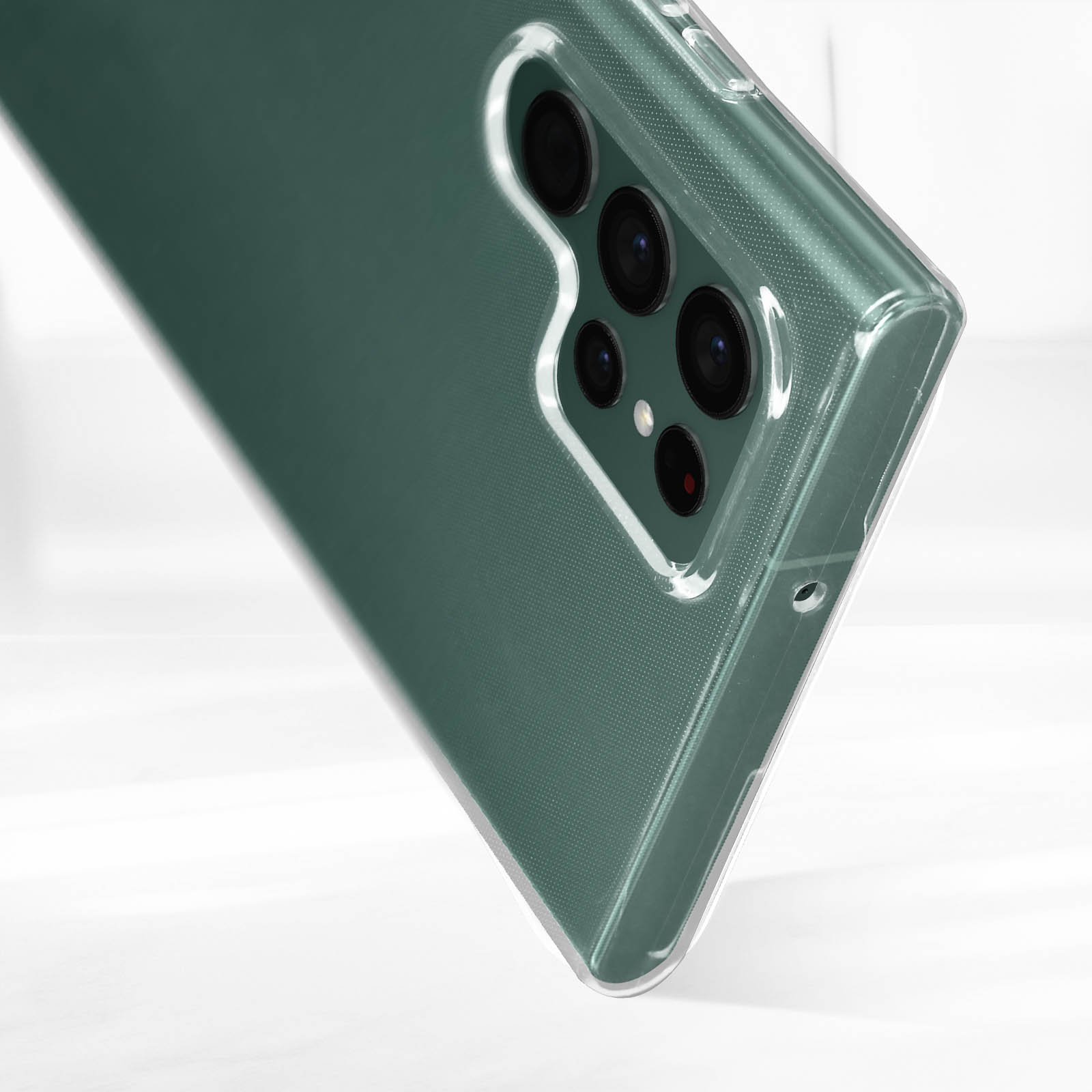 Primo piano di un telefono in una custodia trasparente. Lenti multiple della fotocamera visibili. Superficie bianca sullo sfondo.