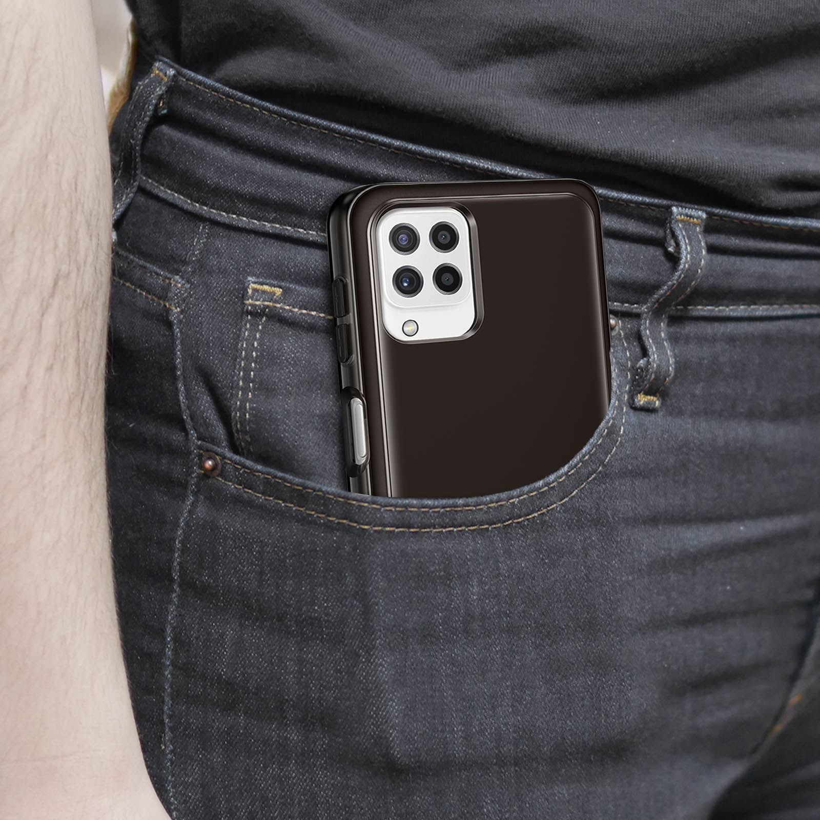 Telefon w czarnym etui jest w kieszeni. Widoczne są ciemne dżinsy.