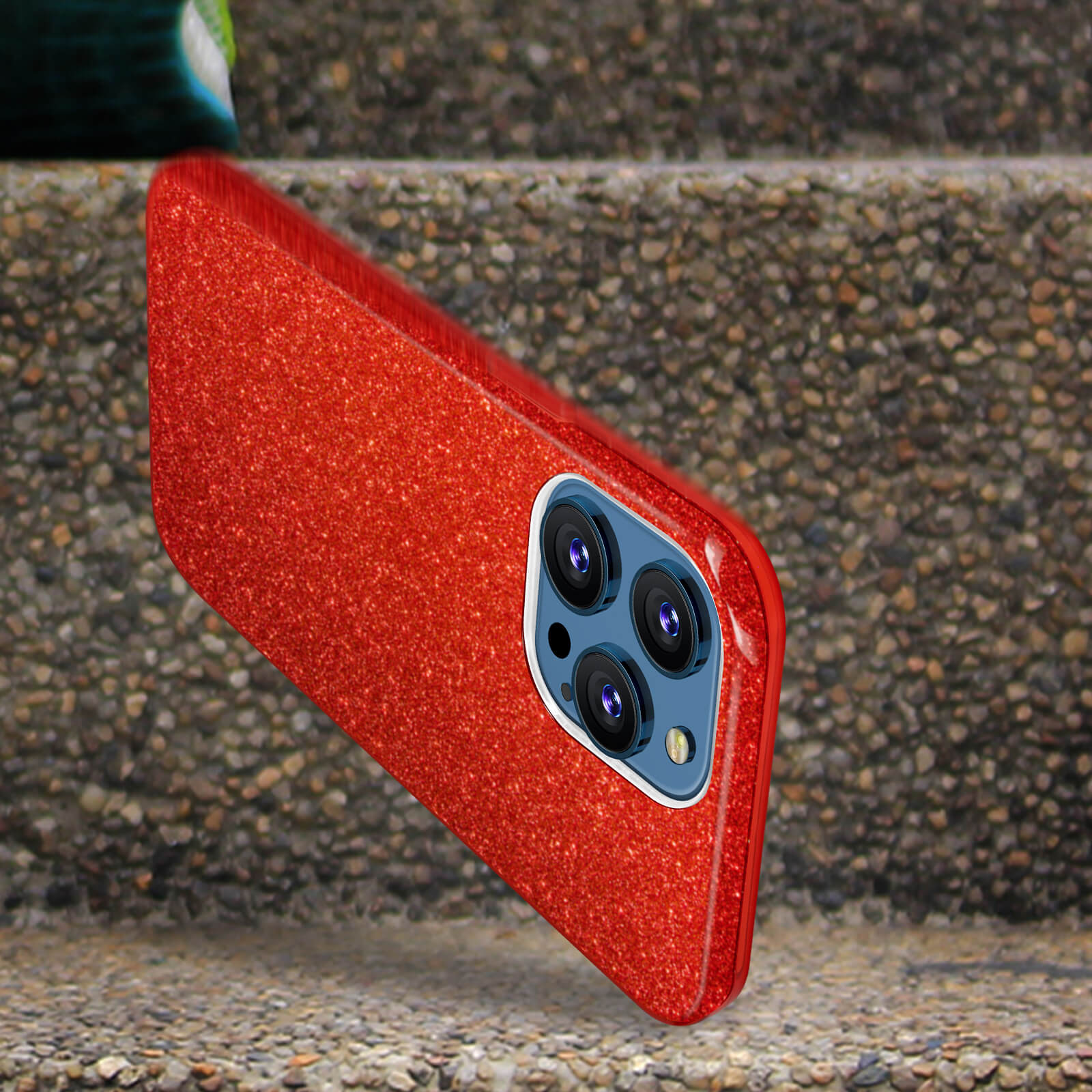 Una custodia per telefono rossa e glitterata con tre lenti della fotocamera. La custodia è su una superficie di pietra.