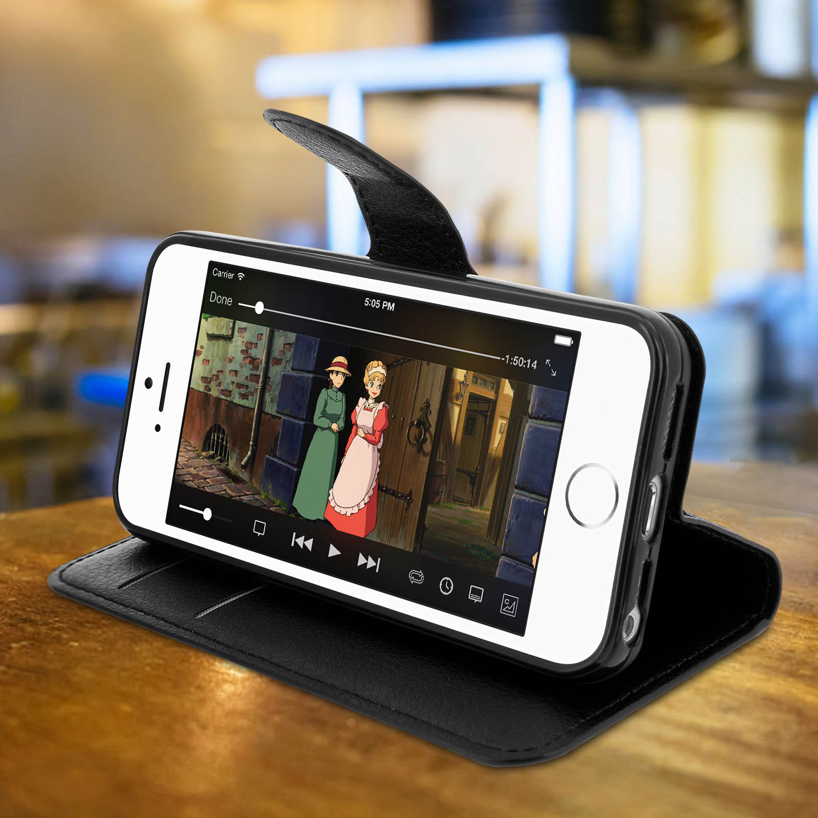 Un iPhone in una custodia nera, che mostra una scena di un film. La custodia è aperta su una superficie di legno.