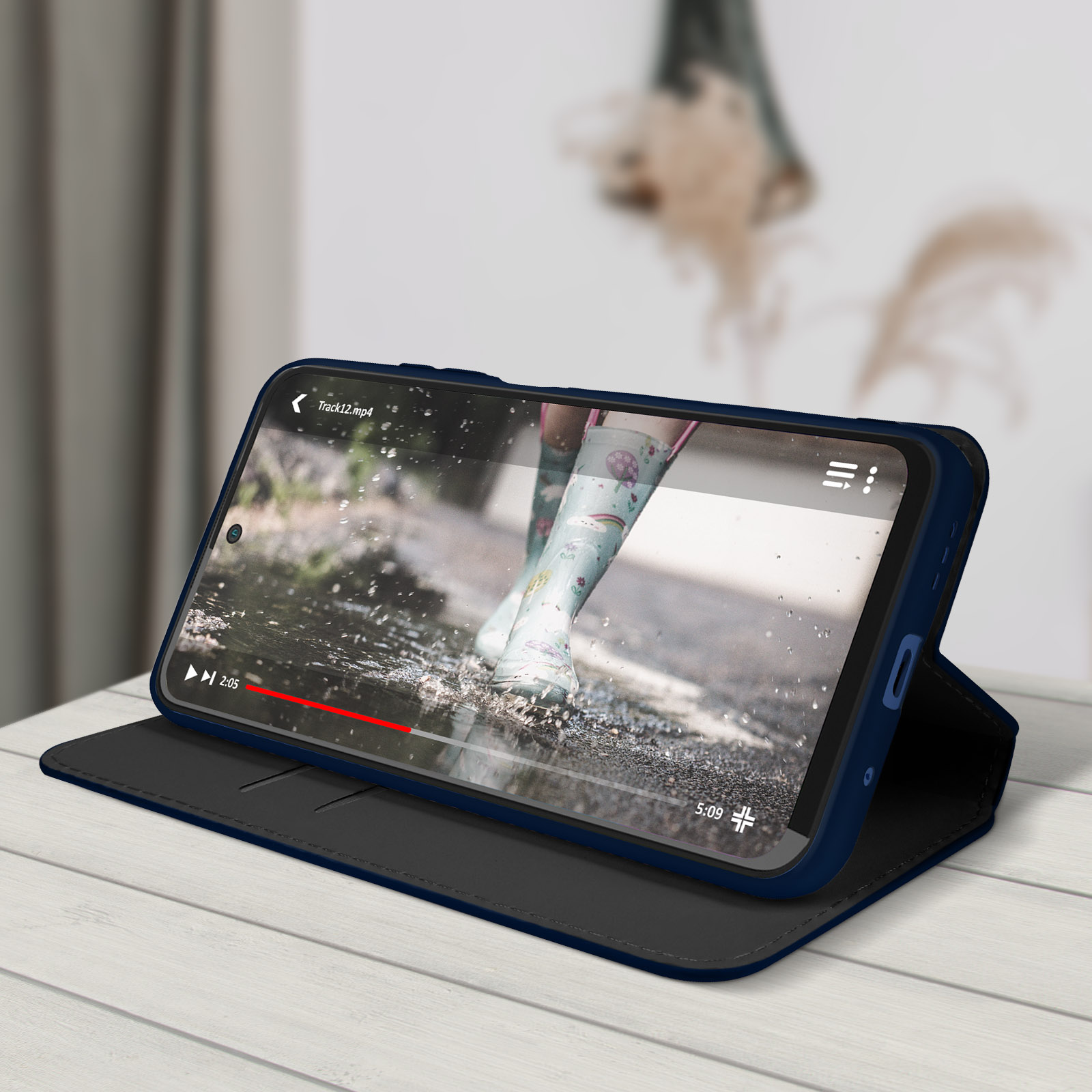 Een telefoon die een video afspeelt, op een tafel, in een blauwe hoes.