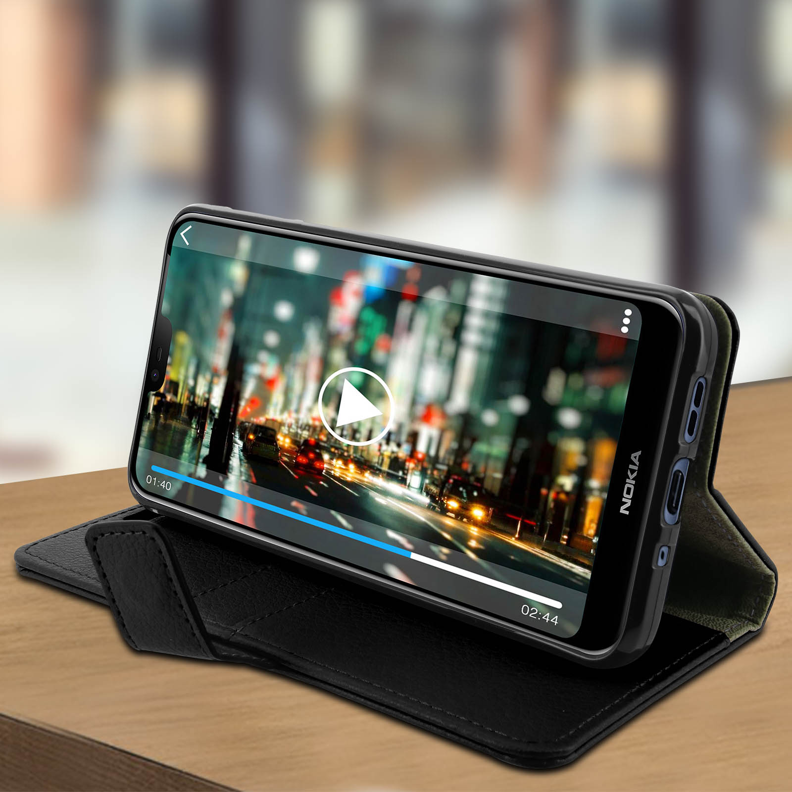 Un telefono Nokia mostra un video su un tavolo. Il telefono è in una custodia nera. Il video mostra una città di notte.