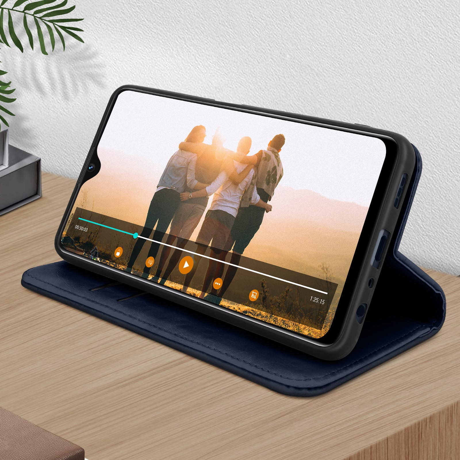 Telefono in custodia blu che mostra video, aperto su superficie in legno.