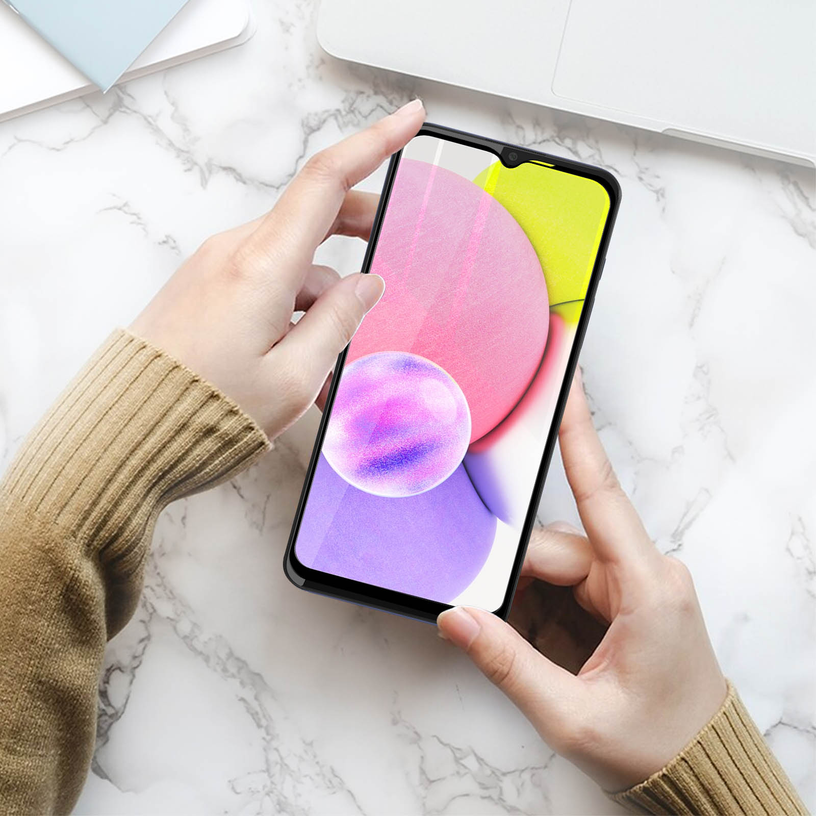 Mains tenant un smartphone affichant des formes abstraites colorées. Le fond est une surface en marbre.