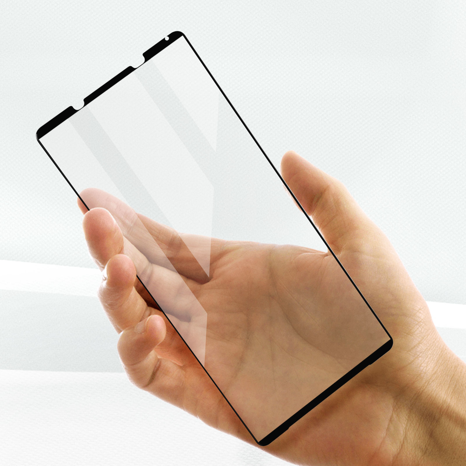 Mano che tiene una protezione schermo trasparente. Bordi neri visibili. Per un telefono.