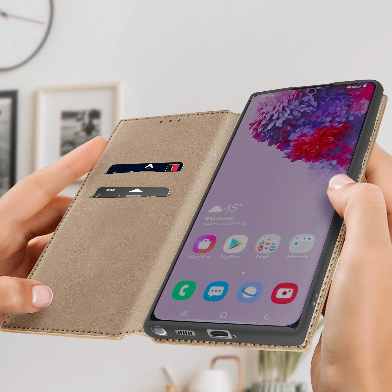 Mani che tengono una custodia marrone con un telefono che mostra l'ora e le app. Carta di debito all'interno.