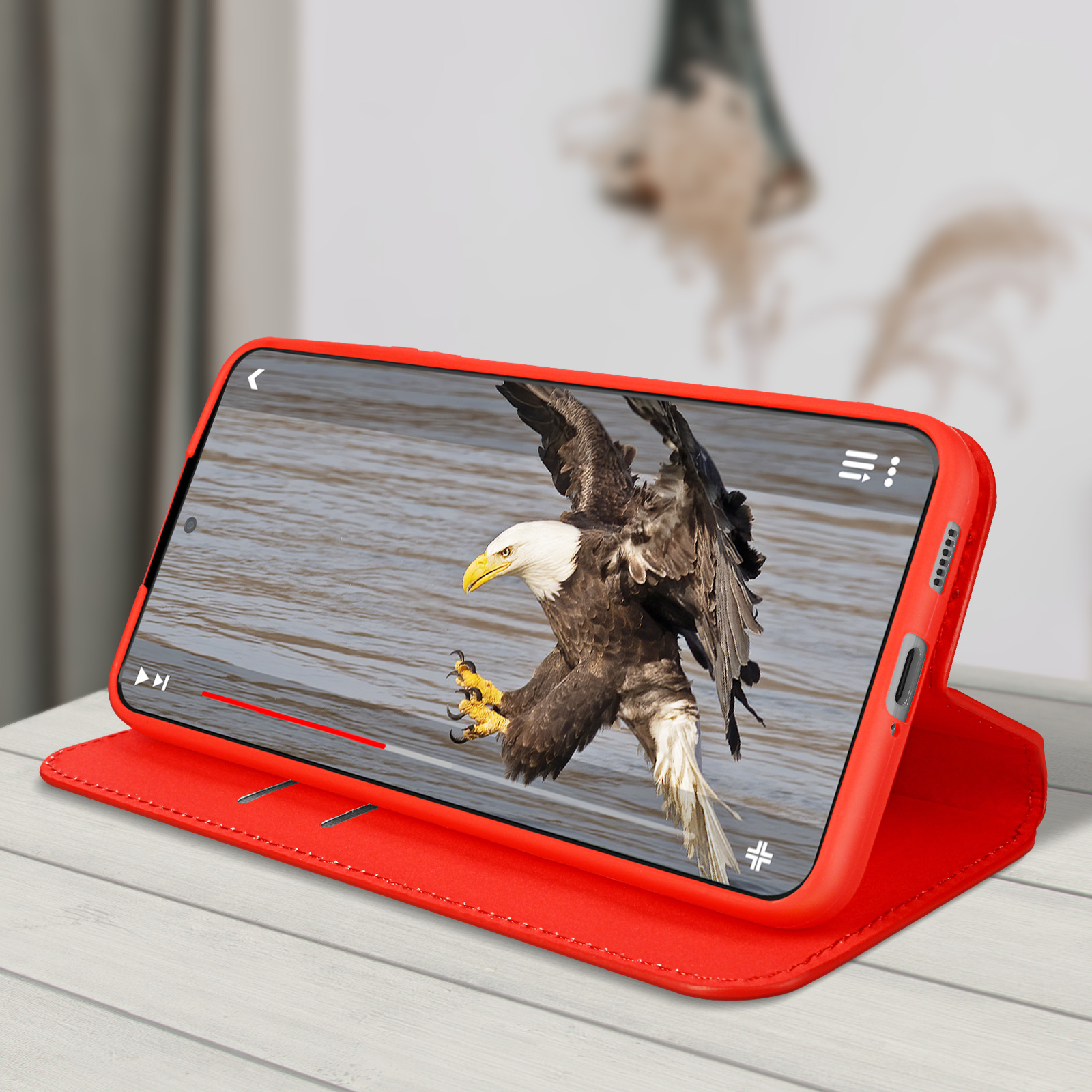 Een telefoon in een rode hoes die een video van een Amerikaanse zeearend afspeelt. De hoes is open.