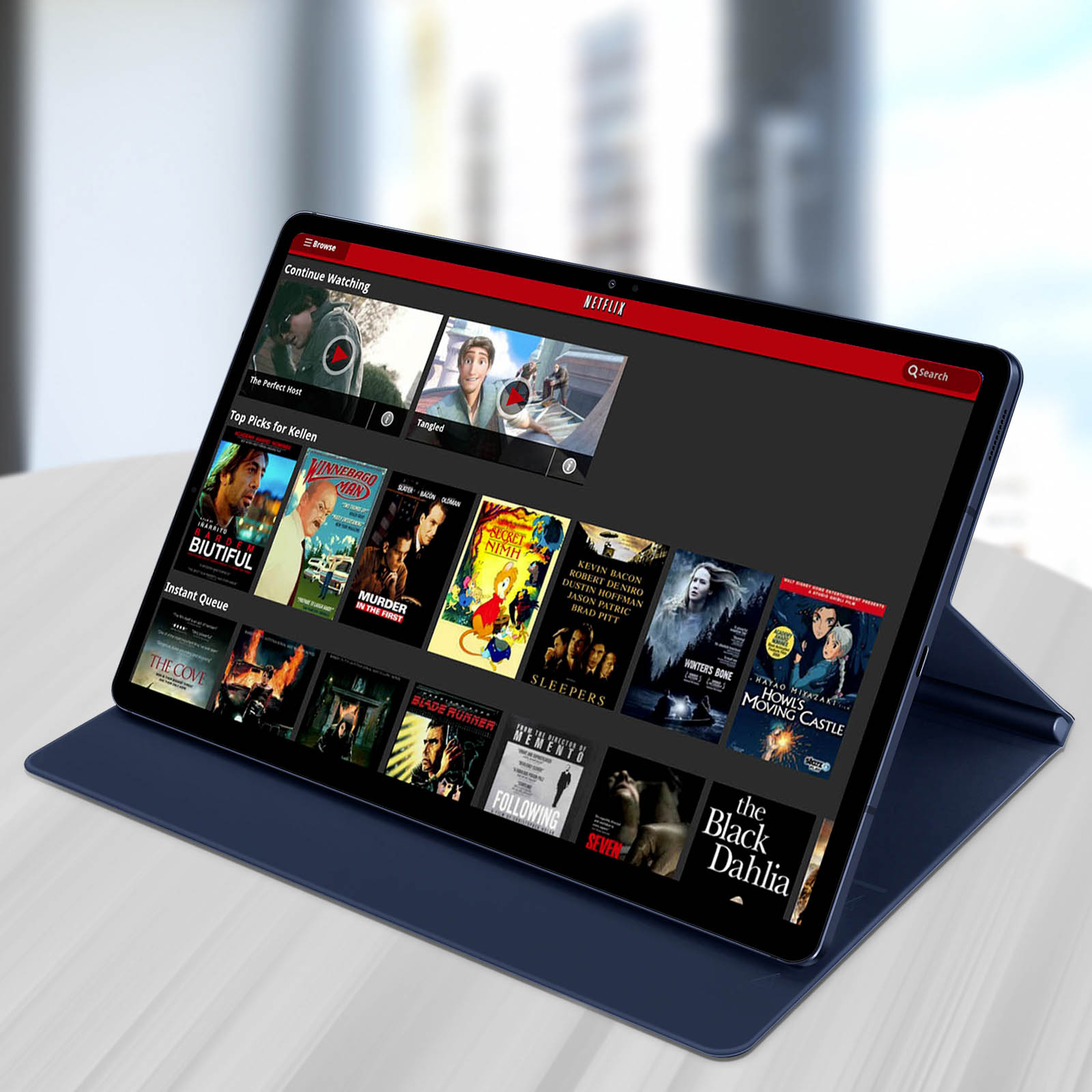 Tablet su un tavolo con l'interfaccia Netflix visualizzata. Lo schermo mostra film. Custodia blu.