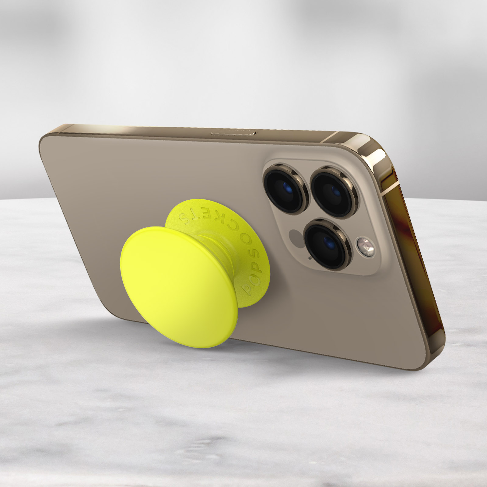 Smartphone mit gelbem PopSocket auf Marmoroberfläche.