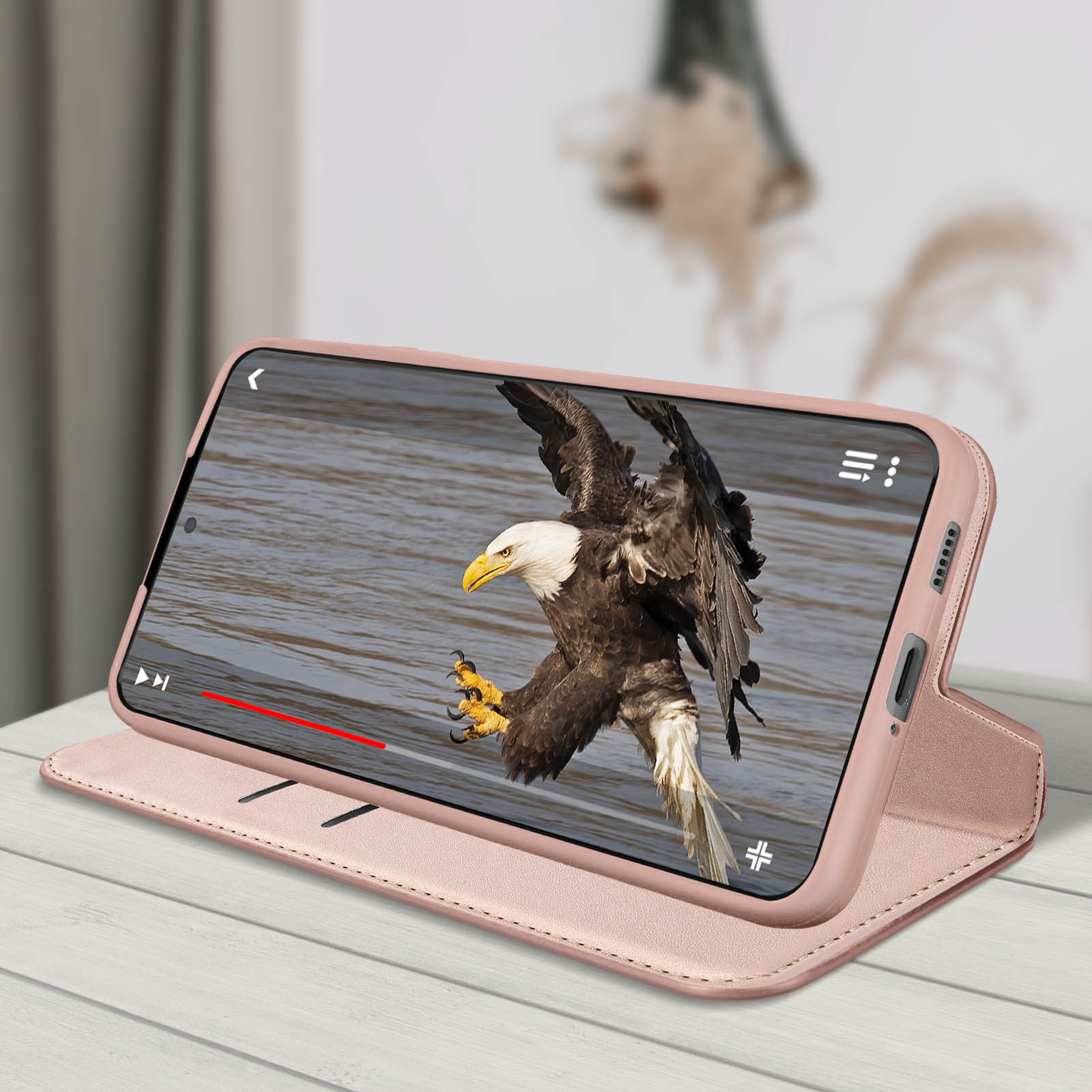 Un téléphone affiche une vidéo d'un aigle, à l'intérieur d'un étui rose. Il est ouvert.