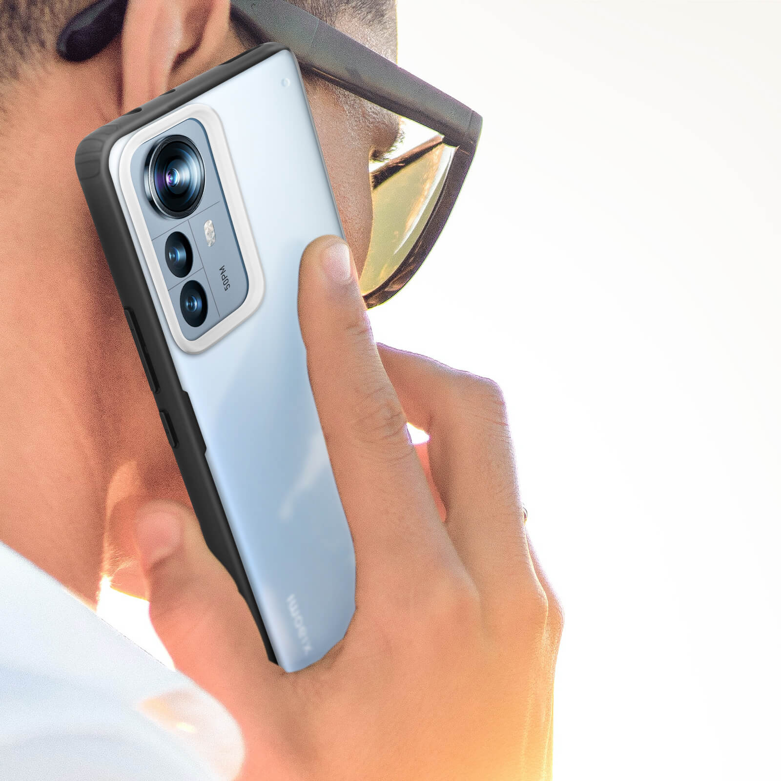 Una persona che tiene un telefono all'orecchio. Il telefono ha una custodia nera.