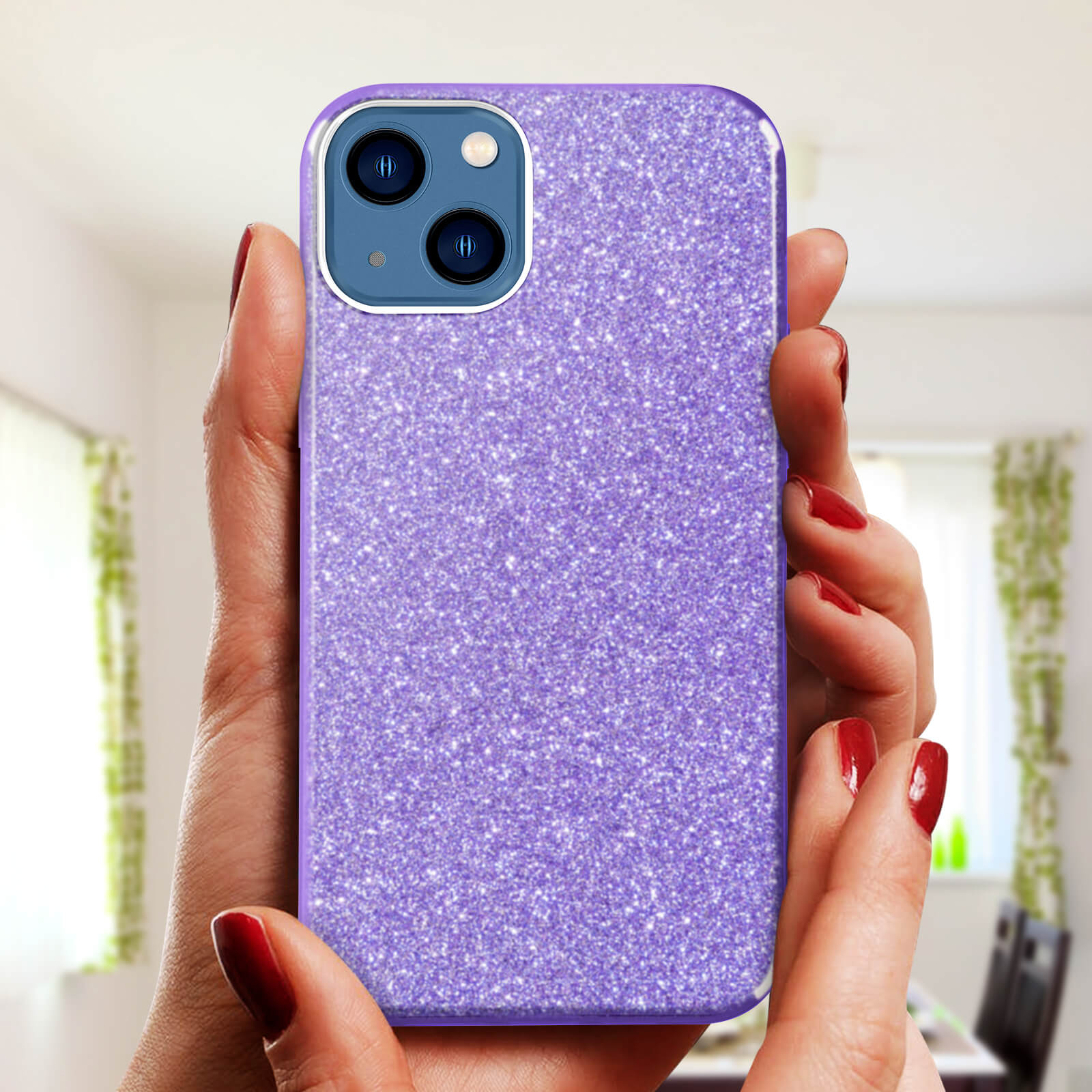 Mani che tengono una custodia per telefono glitterata viola. Smalto rosso sulle dita. Lo sfondo è una stanza.