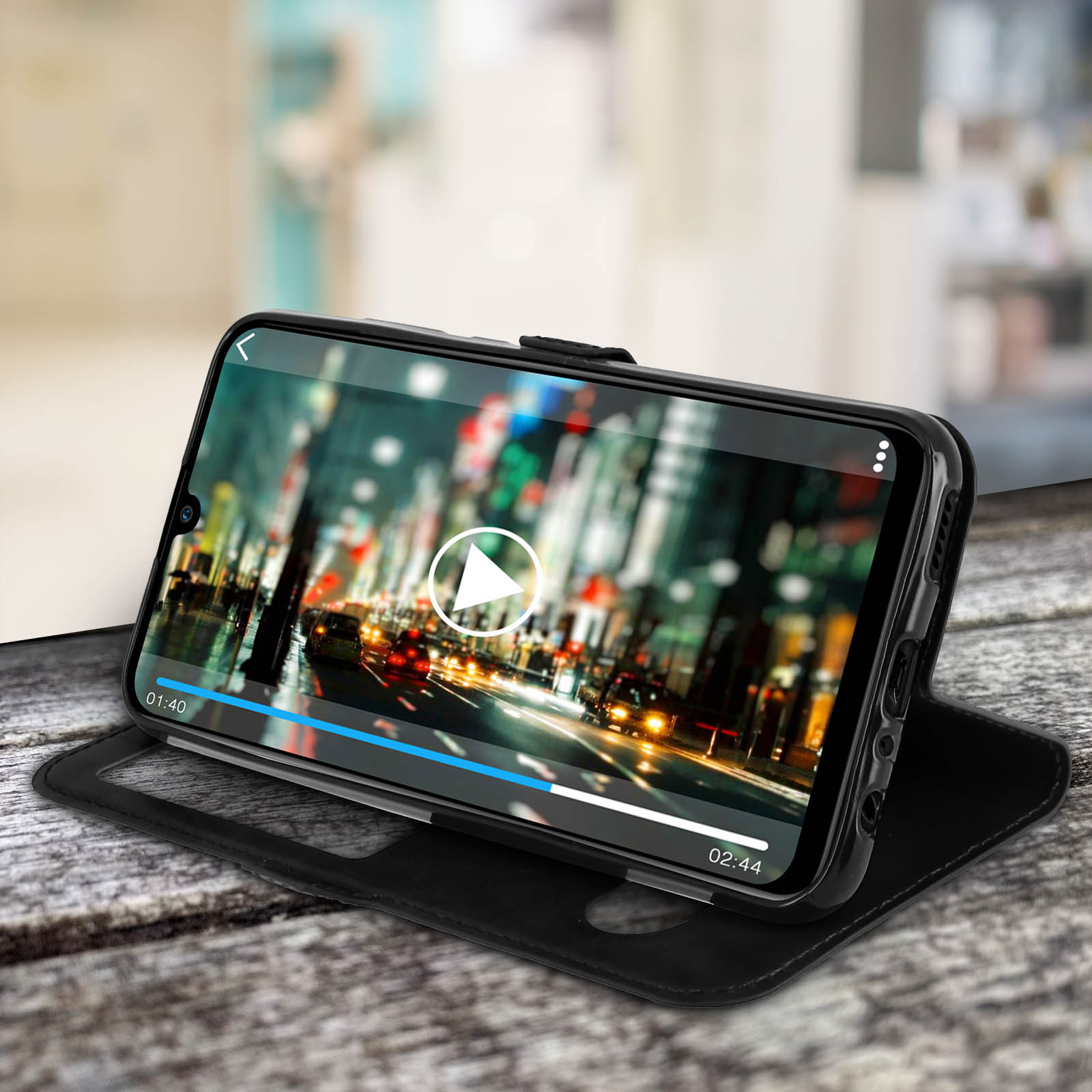 Un telefono in una custodia nera, che mostra un video in riproduzione sullo schermo. La custodia è aperta su un tavolo.